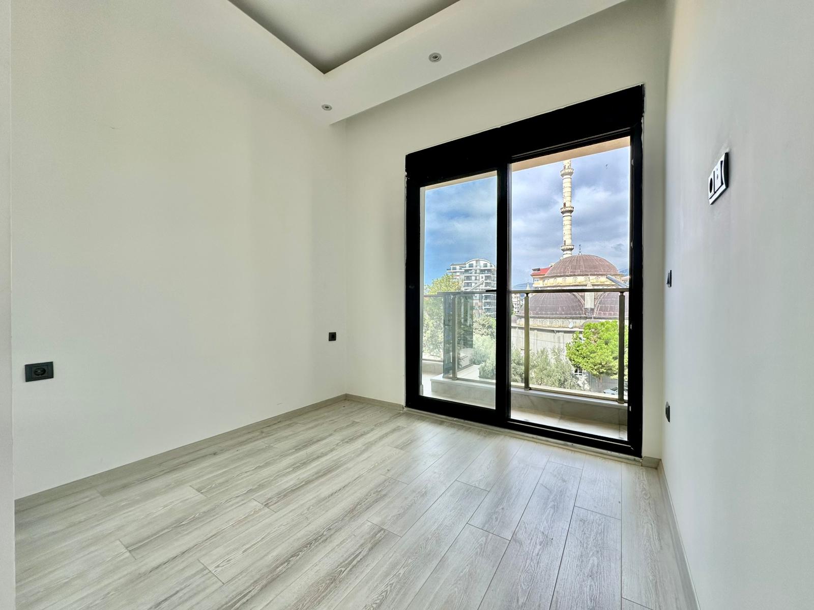 Türkiye’deki dairenin boş odasında panoramik balkon kapısı ve kubbeli minare manzarası