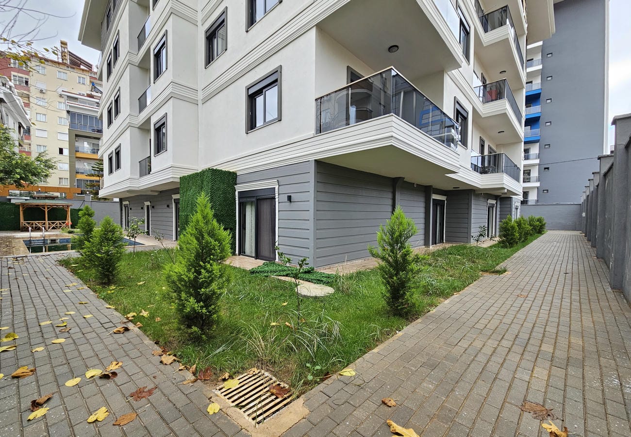 Türkiye’de satıştaki binanın yan cephesinde panoramik kapılar, çim alan ve havuz kenarı