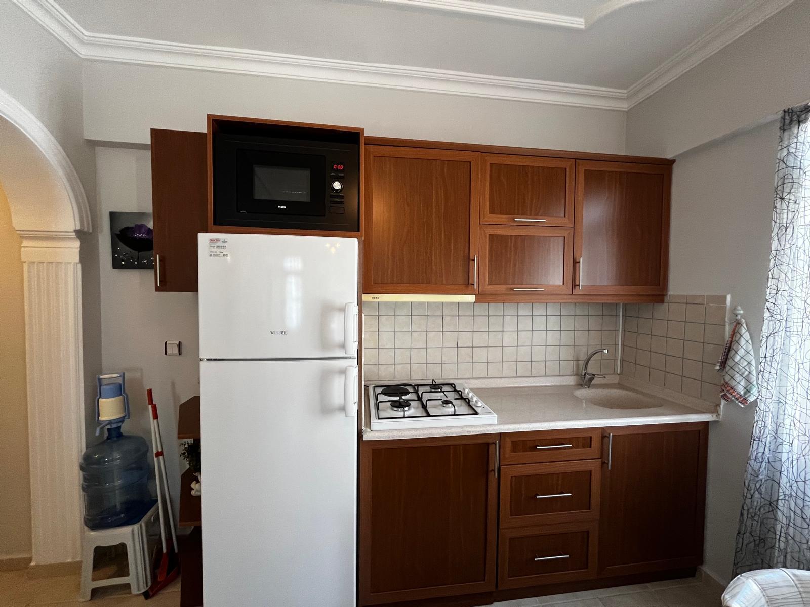Alanya’daki rezidansın mutfağında ahşap dolaplar, yuvarlak evye ve gazlı ocak