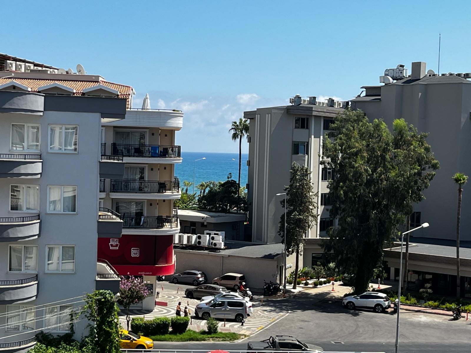 Türkiye’de Alanya’daki rezidans yakınında palmiyeler ve binalar arasından deniz manzarası