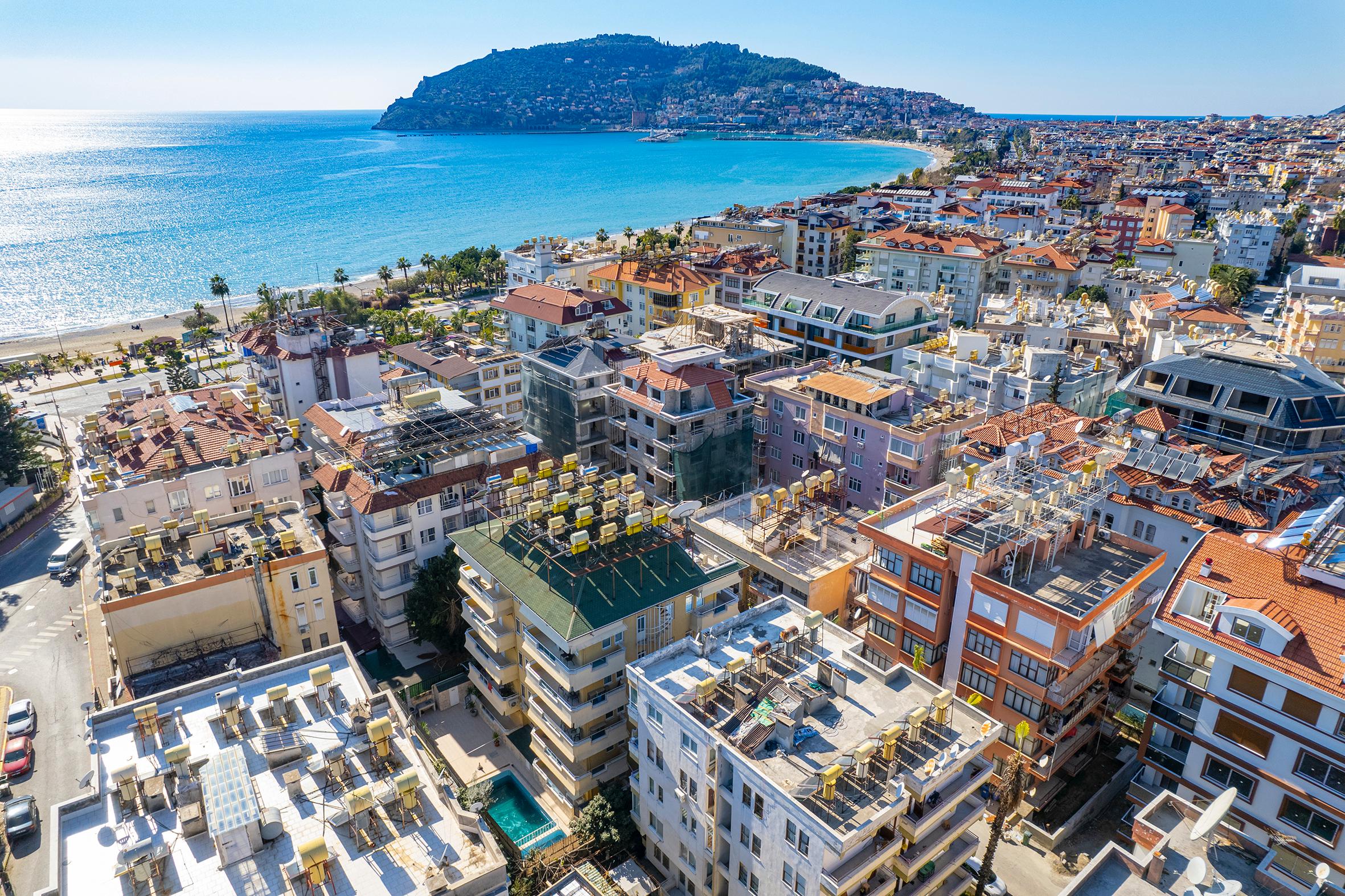 Sahil yerleşimi, kumlu plaj ve mavi koy manzarası: Alanya’da satılık daire, Türkiye — New Level Group