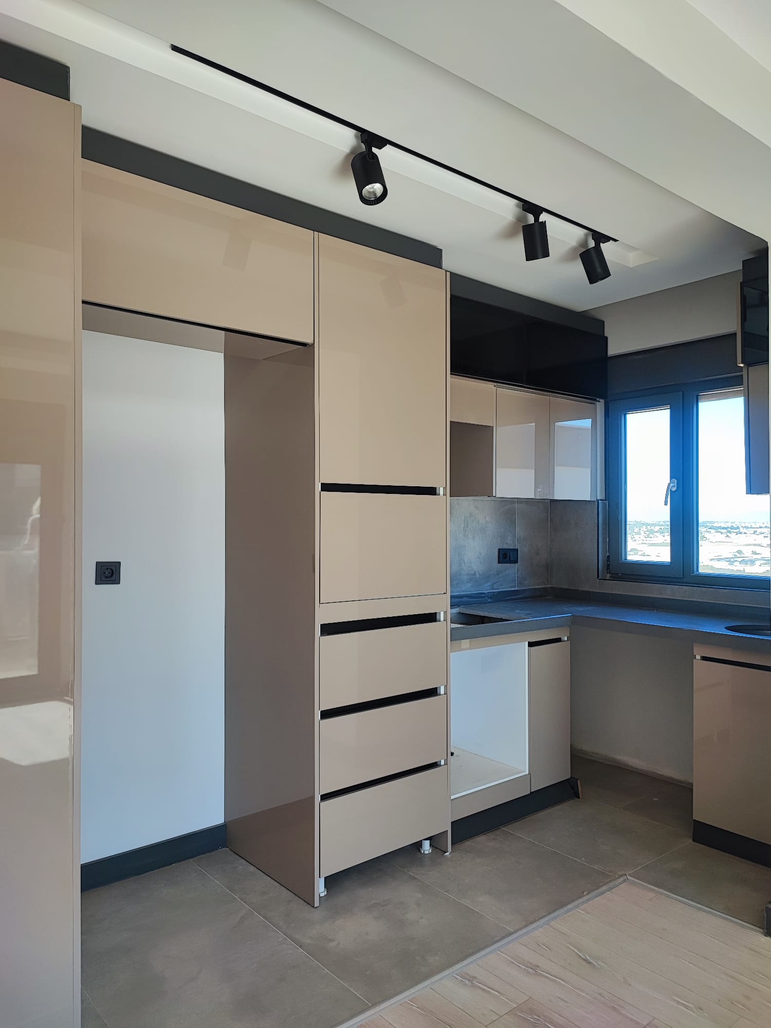 Kitchen in an apartment with beige corner cabinetry, graphite upper units and a gray countertop