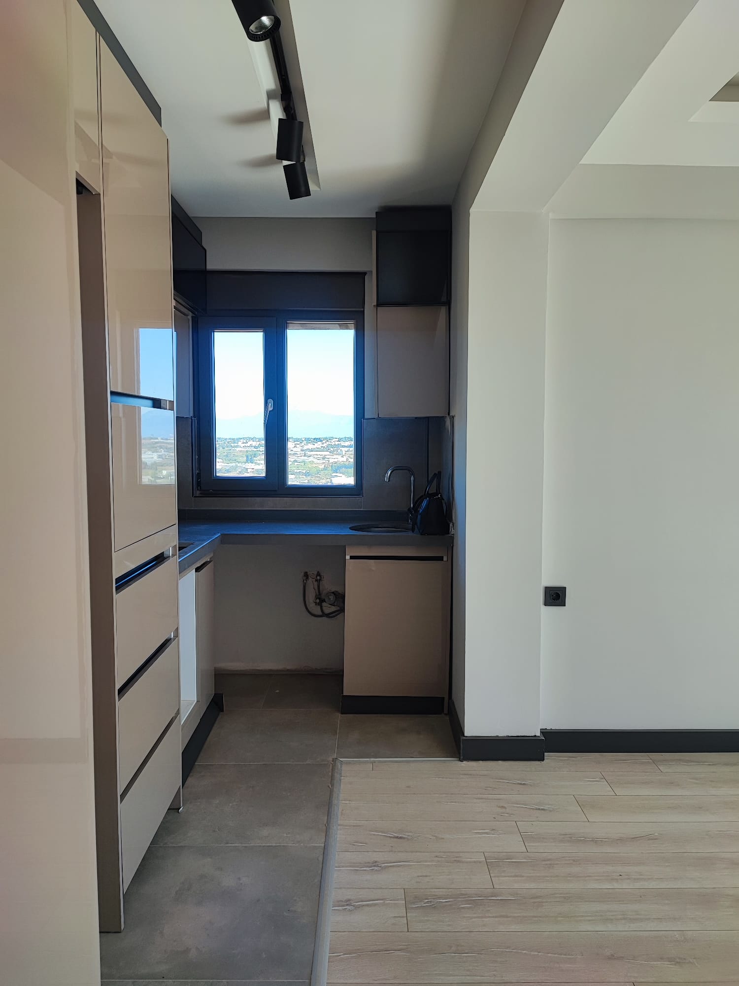 Compact kitchen with sink connections under the window and black track lights in Antalya