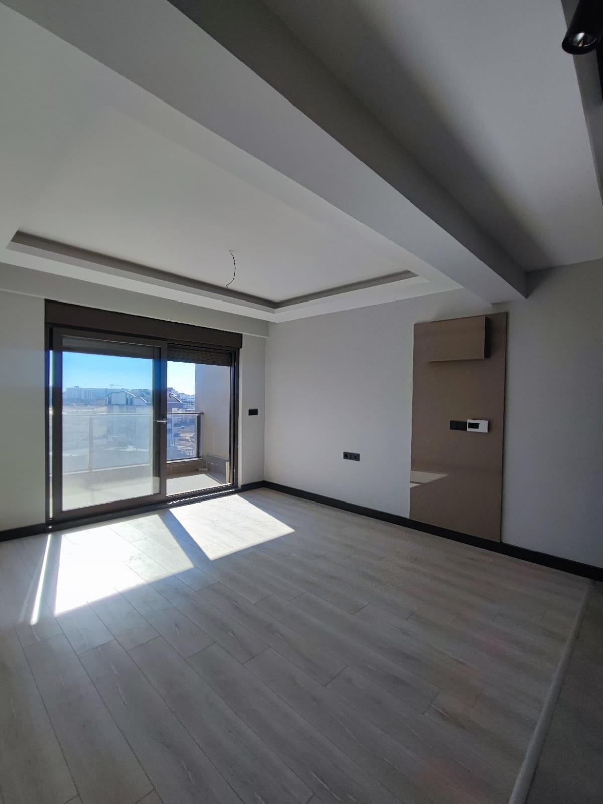 Living room of a 1+1 home in Türkiye with balcony access and a gray accent wall