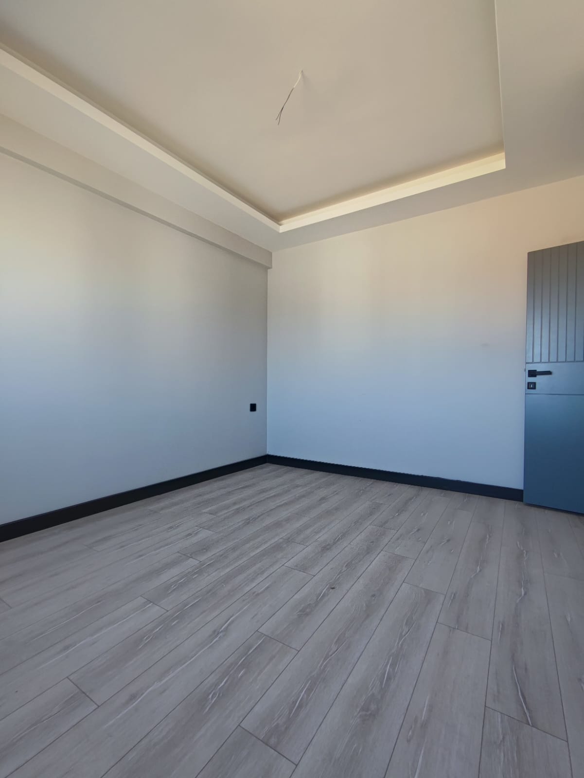 Bedroom with gray laminate flooring, a grooved gray door and perimeter ceiling lighting