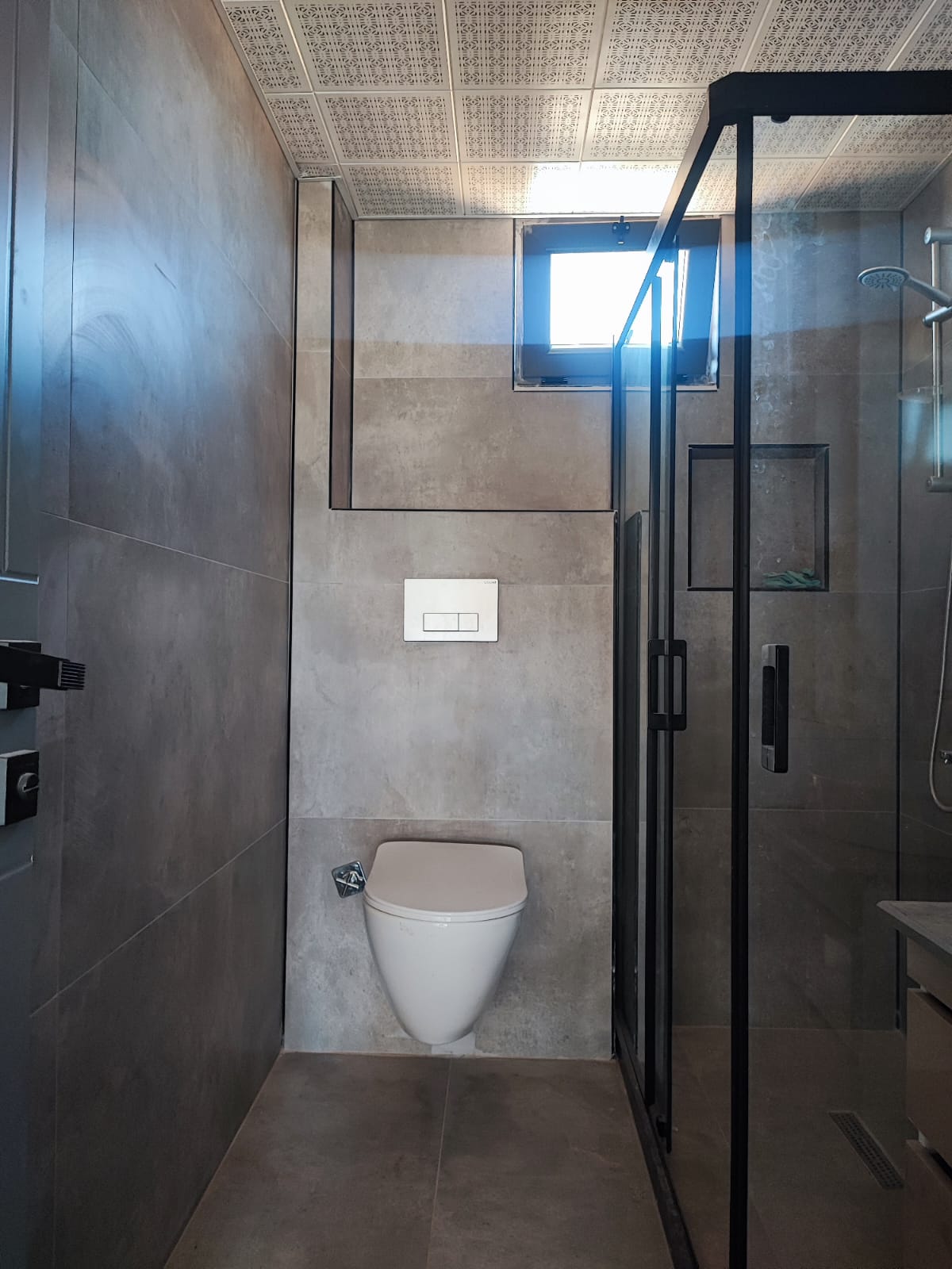 Bathroom in a home with wall-hung toilet and black-framed shower enclosure