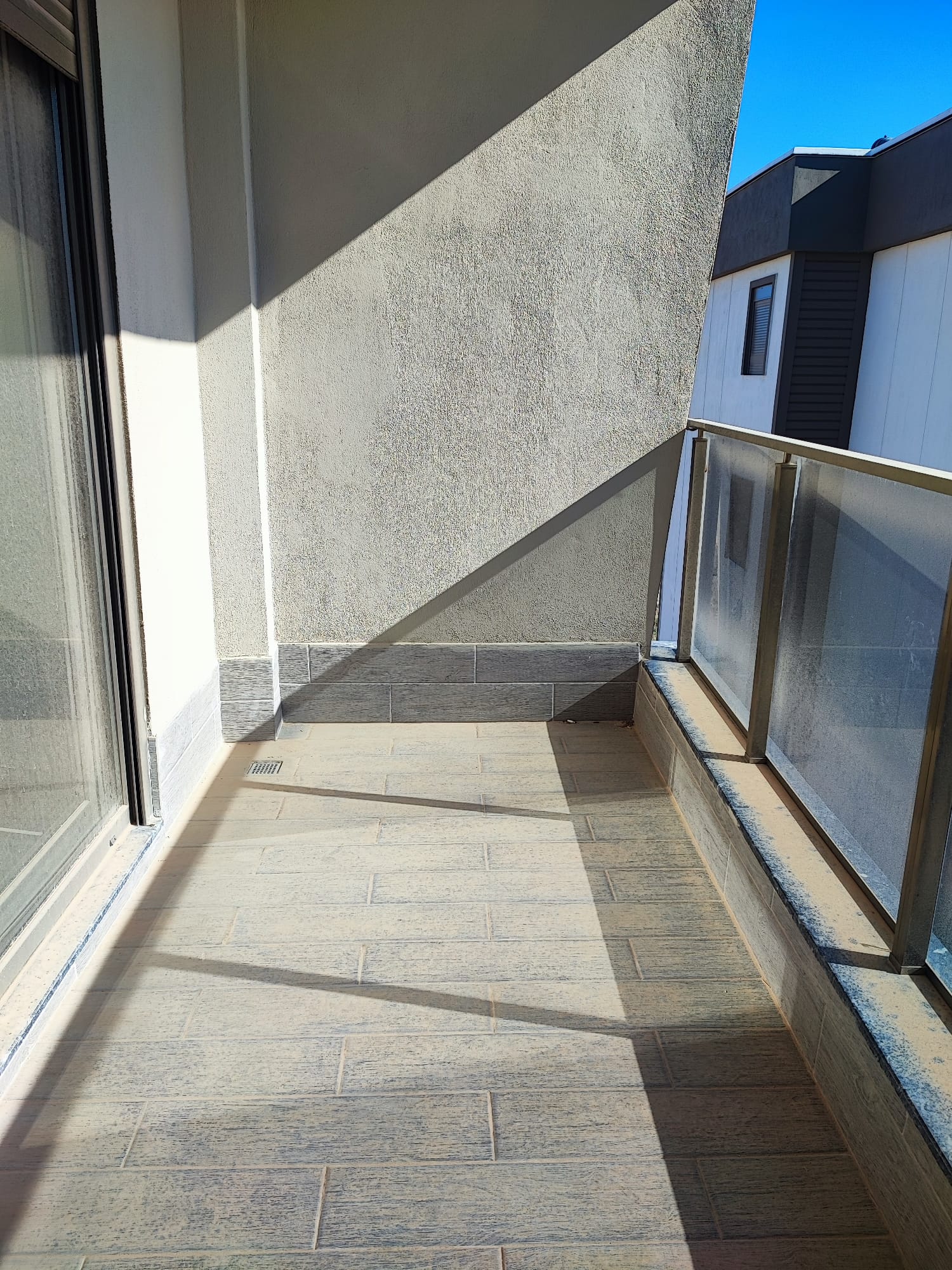 Narrow open balcony of a 1+1 apartment for sale in Turkey with frosted glass railing