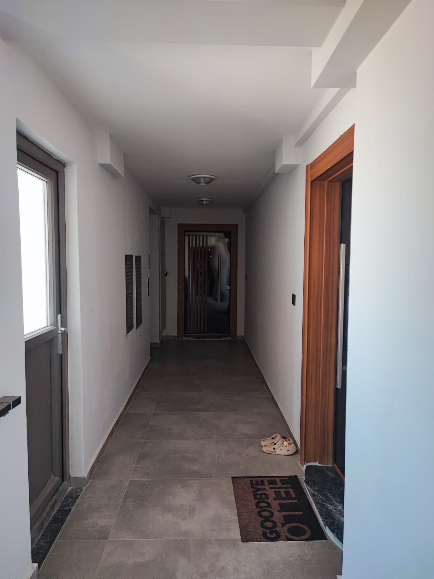 Corridor with white walls and gray tile flooring in a complex with apartments in Antalya