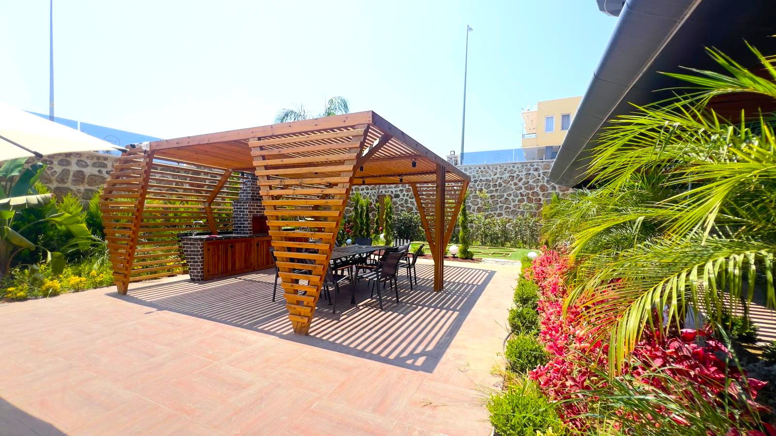Türkiye’nin Alanya kentindeki konut rezidansında yemek masalı ahşap pergola ve palmiyeli dinlenme alanı