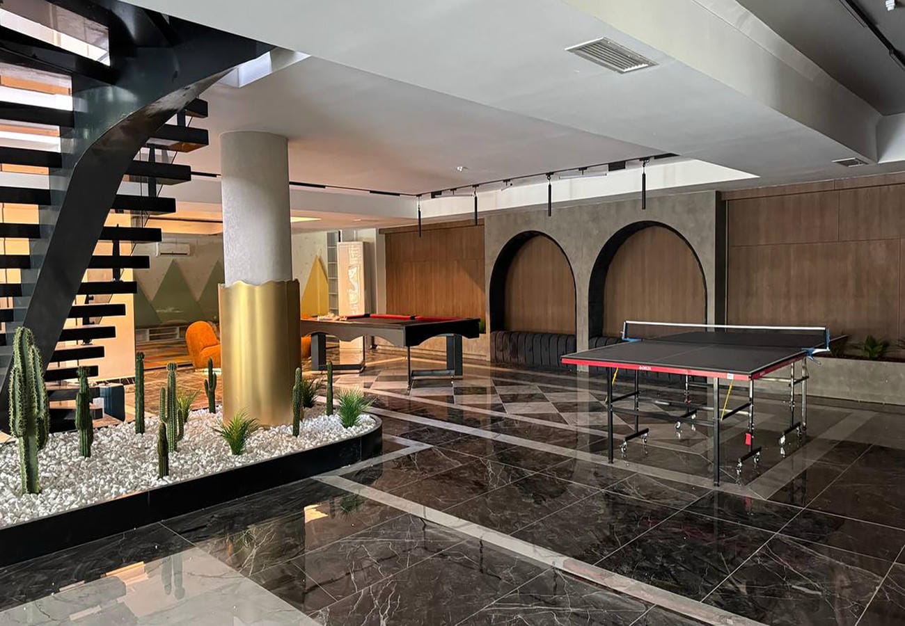 Bilardo odasında fileli masa tenisi masası, arkada bilardo masası ve kaktüslü dekoratif çiçeklik