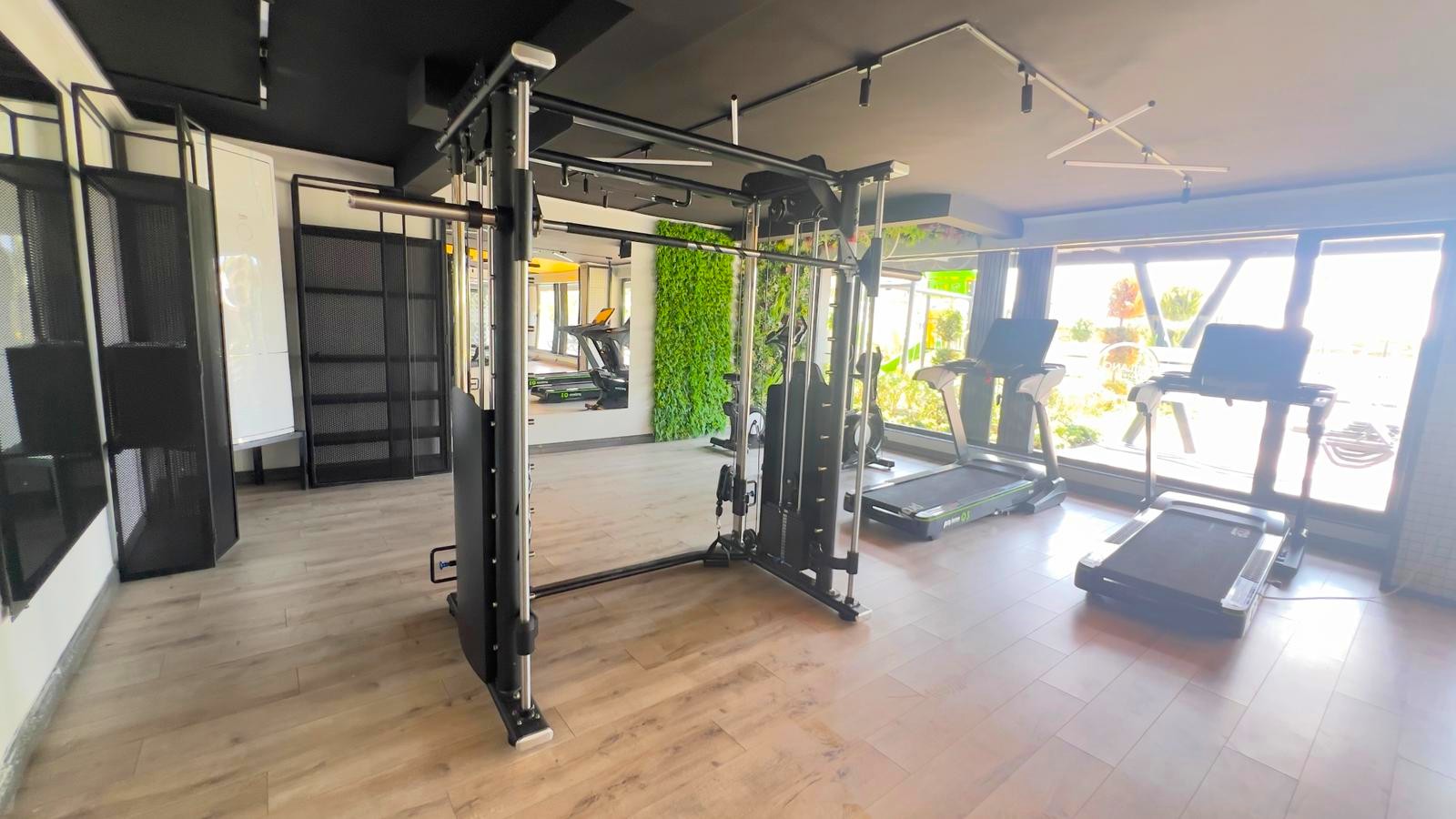 Apartman sakinleri için spor salonunda güç istasyonu, panoramik pencere önünde koşu bantları ve aynalı duvar
