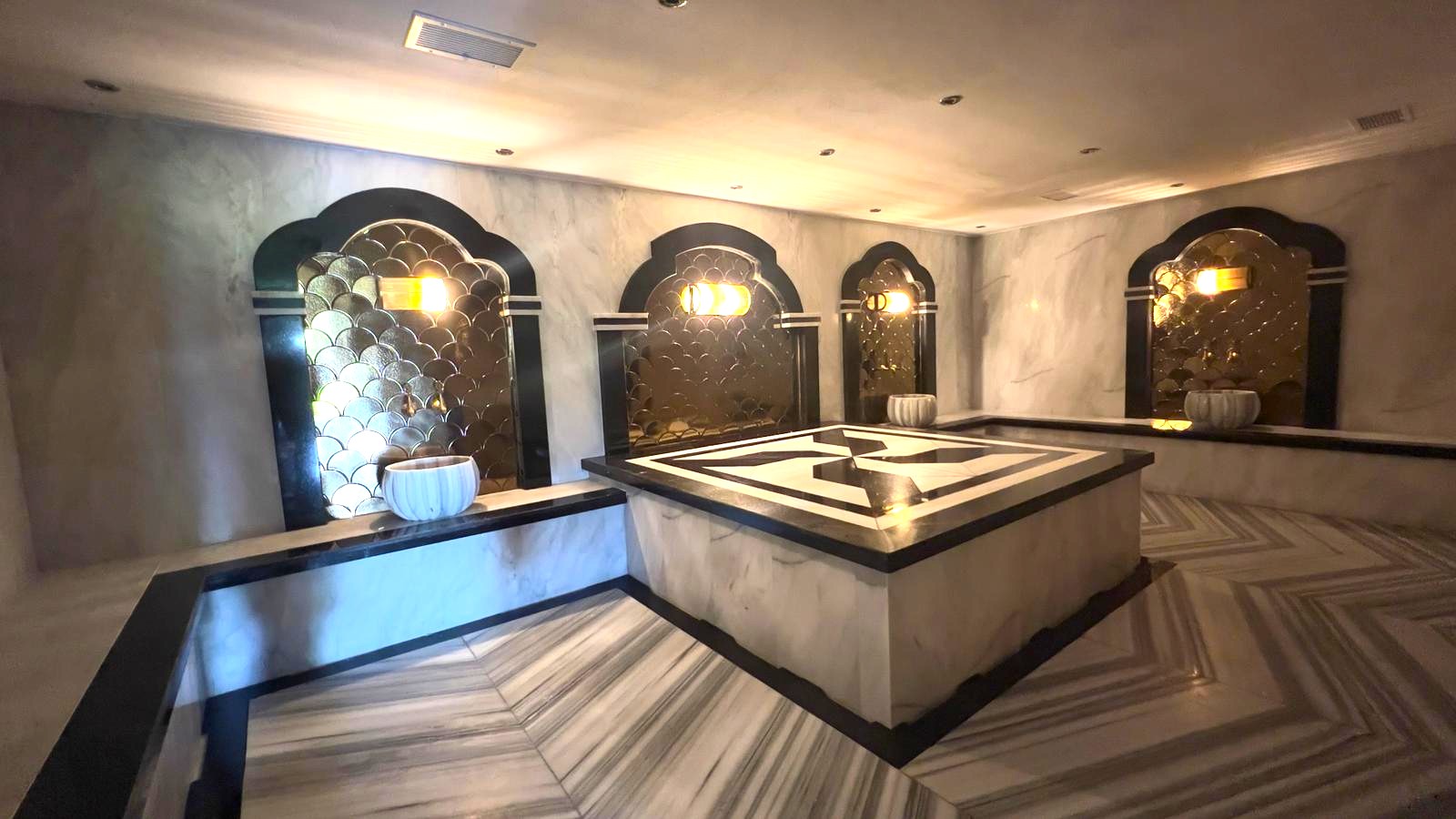 Hamamda merkezi mermer platform, aynalı mozaikli üç kemerli niş ve gömme mermer oturma bankları