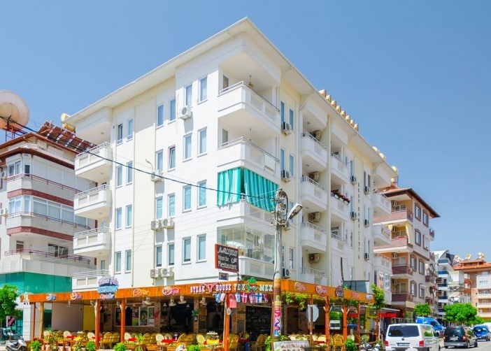 Beş katlı beyaz cephe ve köşe balkonlar: Alanya’nın deniz kenarında satılık 1+1 daire, Türkiye — New Level Group