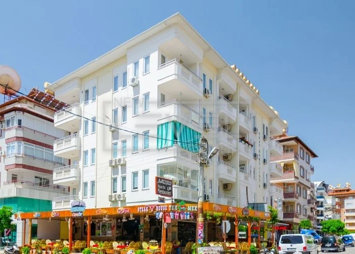 Beş katlı beyaz cephe ve köşe balkonlar: Alanya’nın deniz kenarında satılık 1+1 daire, Türkiye — New Level Group