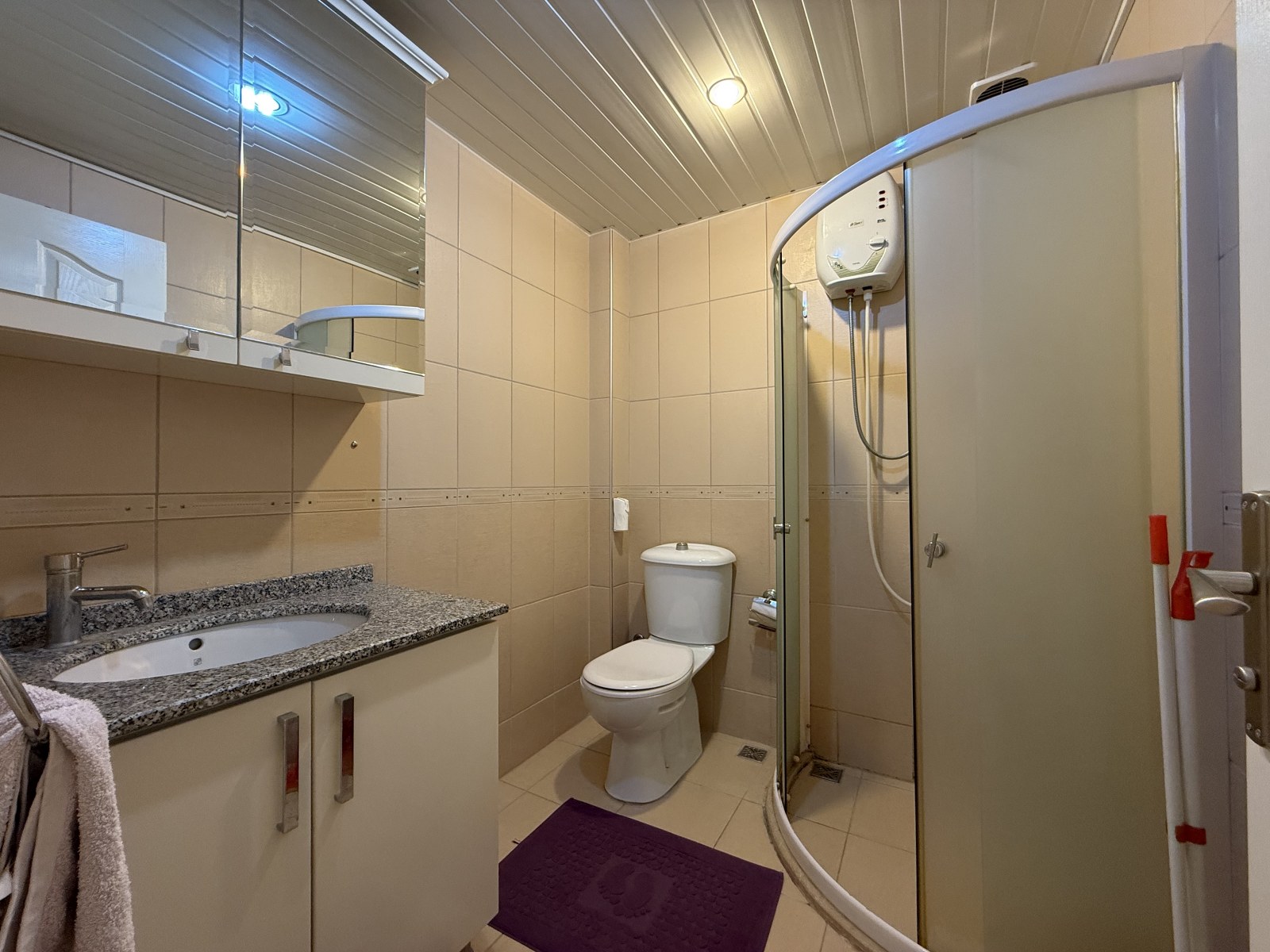 1+1 dairenin banyosunda buzlu camlı duş kabini, granit tezgâh ve oval gömme lavabo