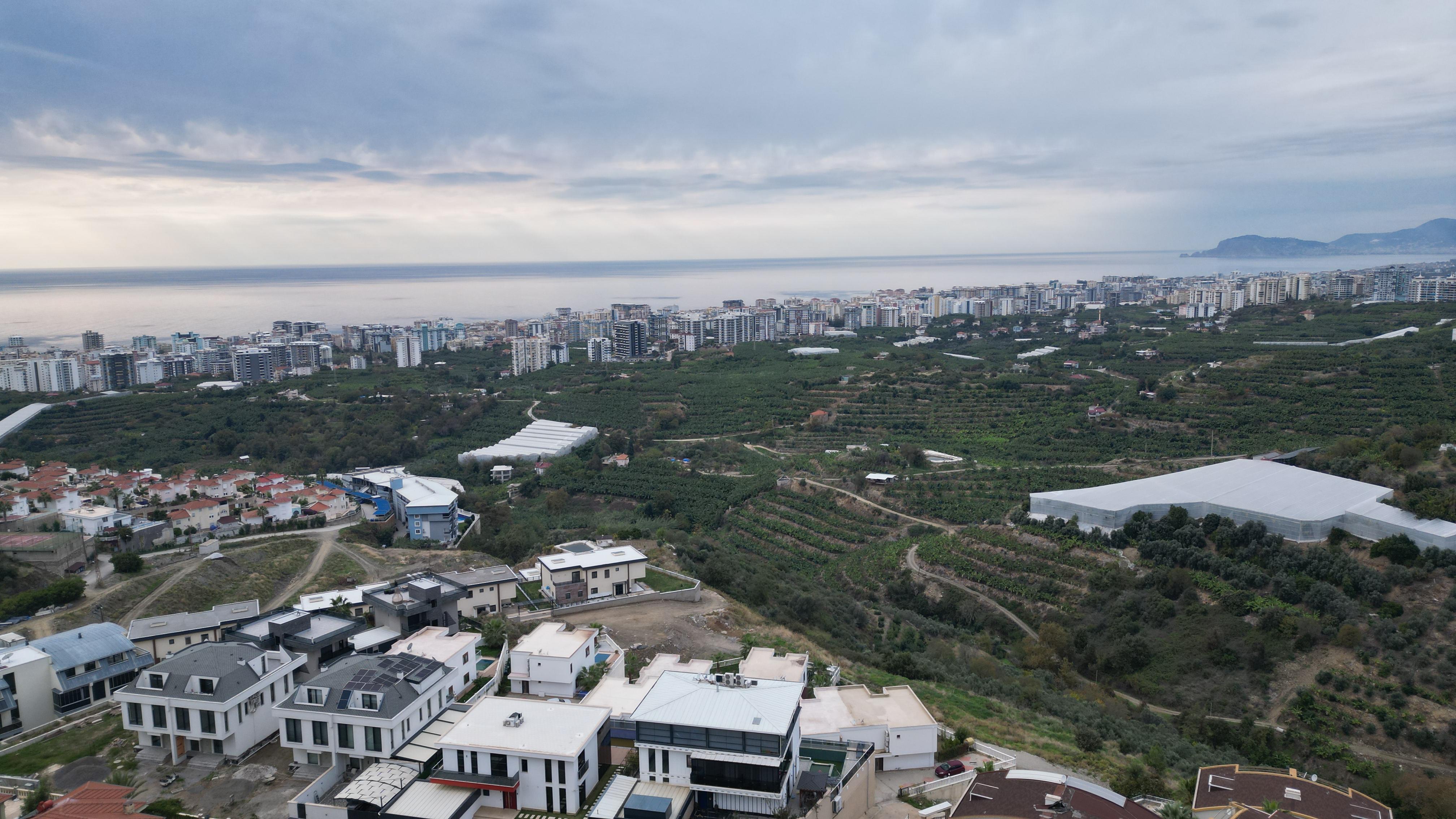 Panoramic coastal view with private homes, green gardens and sea on the horizon in a villa in Turkey