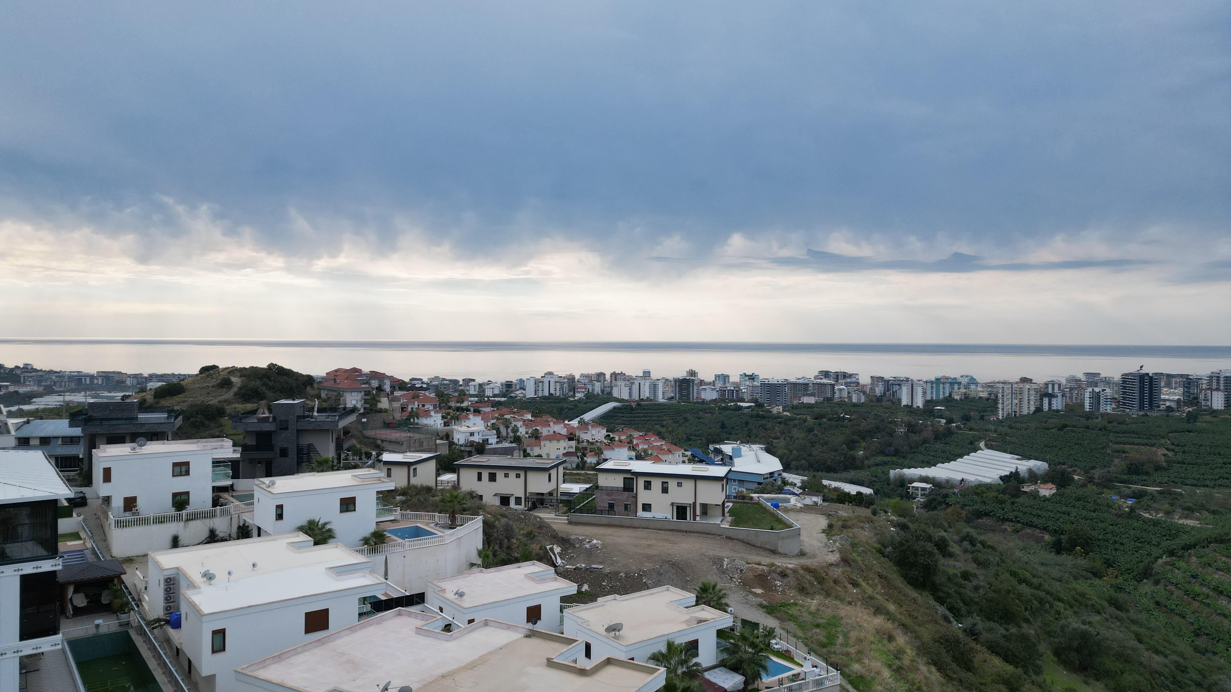 Aerial view of modern private homes and hillside gardens with sea views from a villa in Turkey for sale