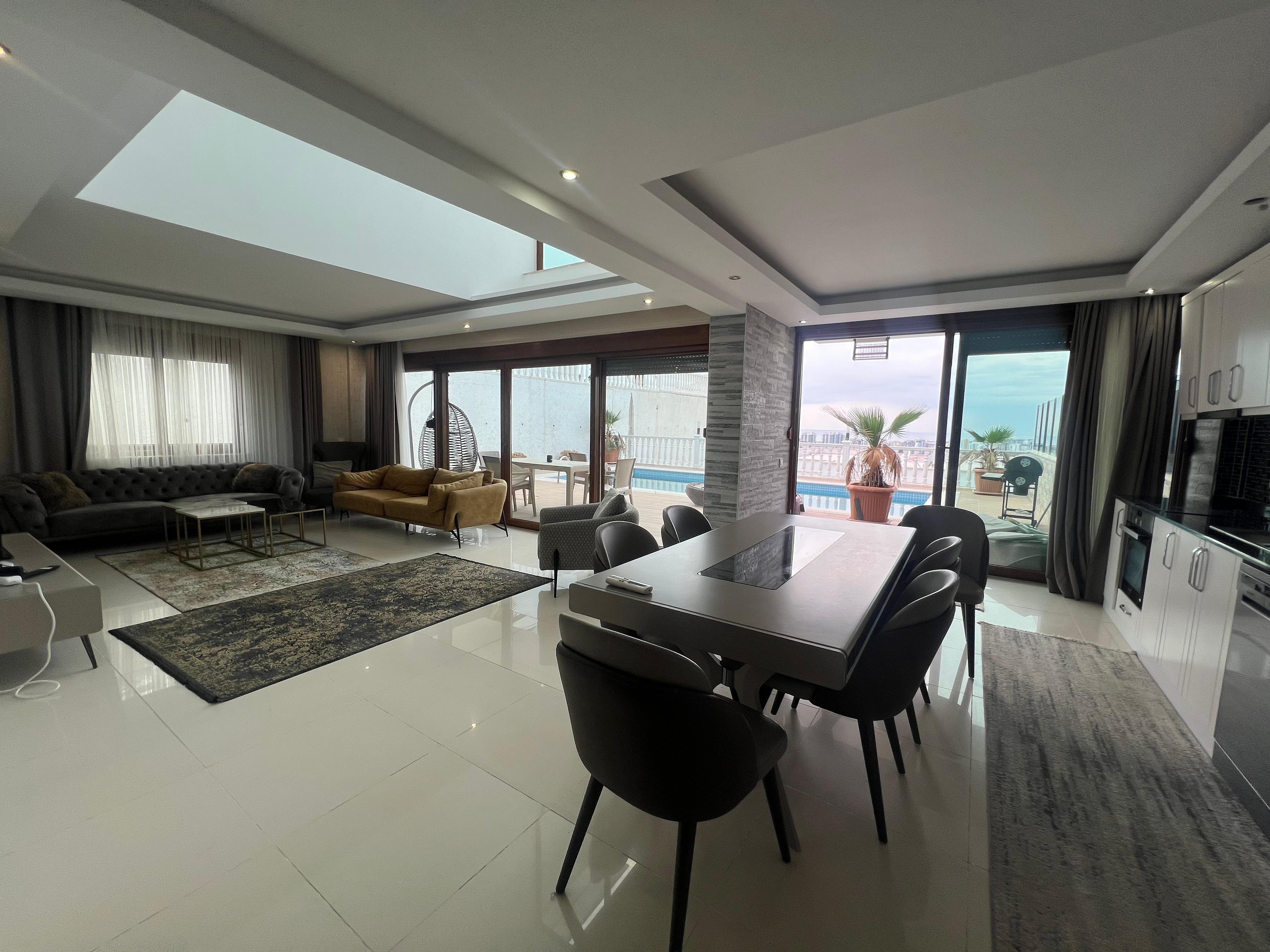 Kitchen-living room with a dining table, terrace access and panoramic windows in a villa in Turkey