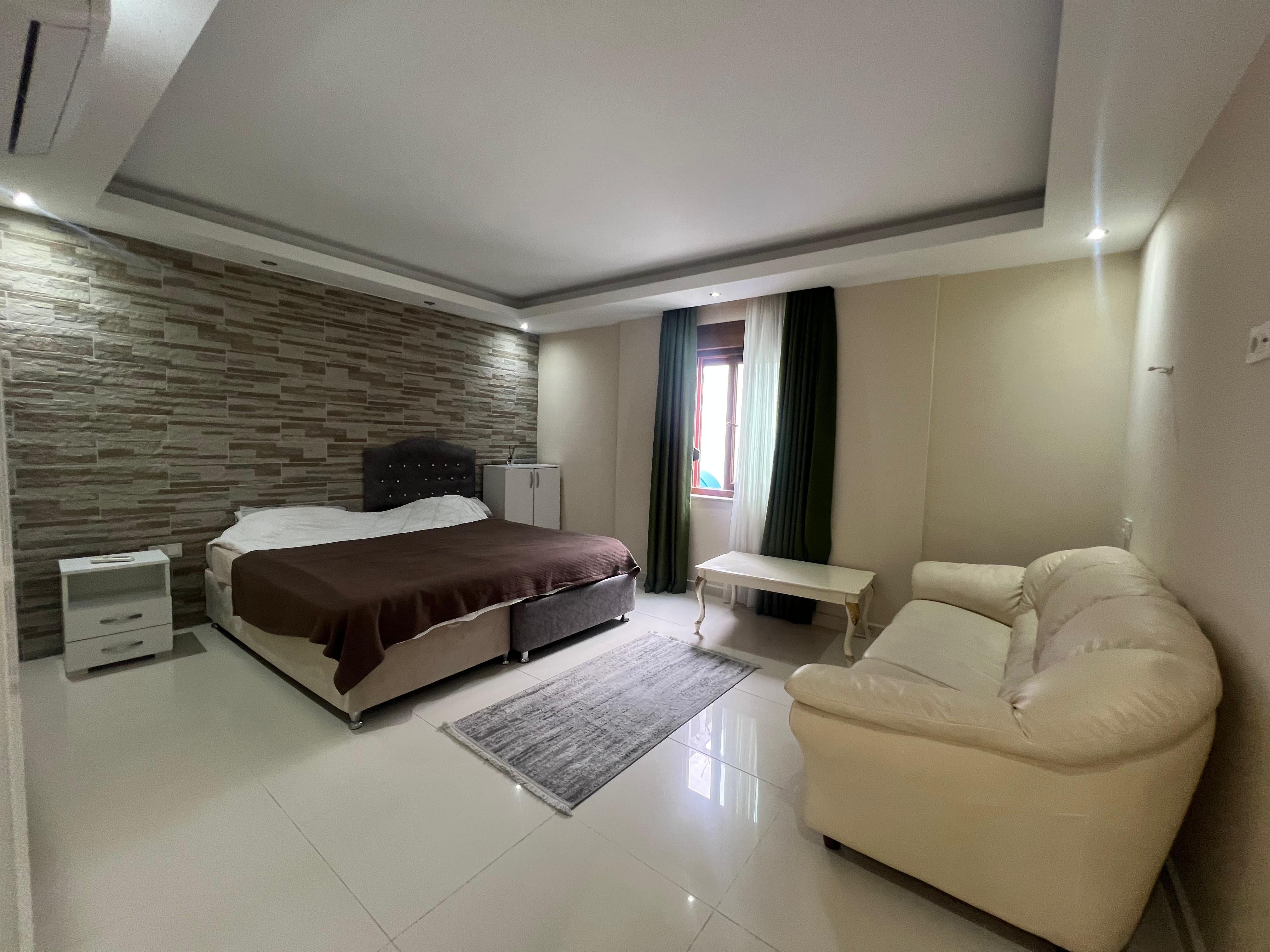 Bedroom with a double bed, upholstered headboard and stone-effect accent wall in a house