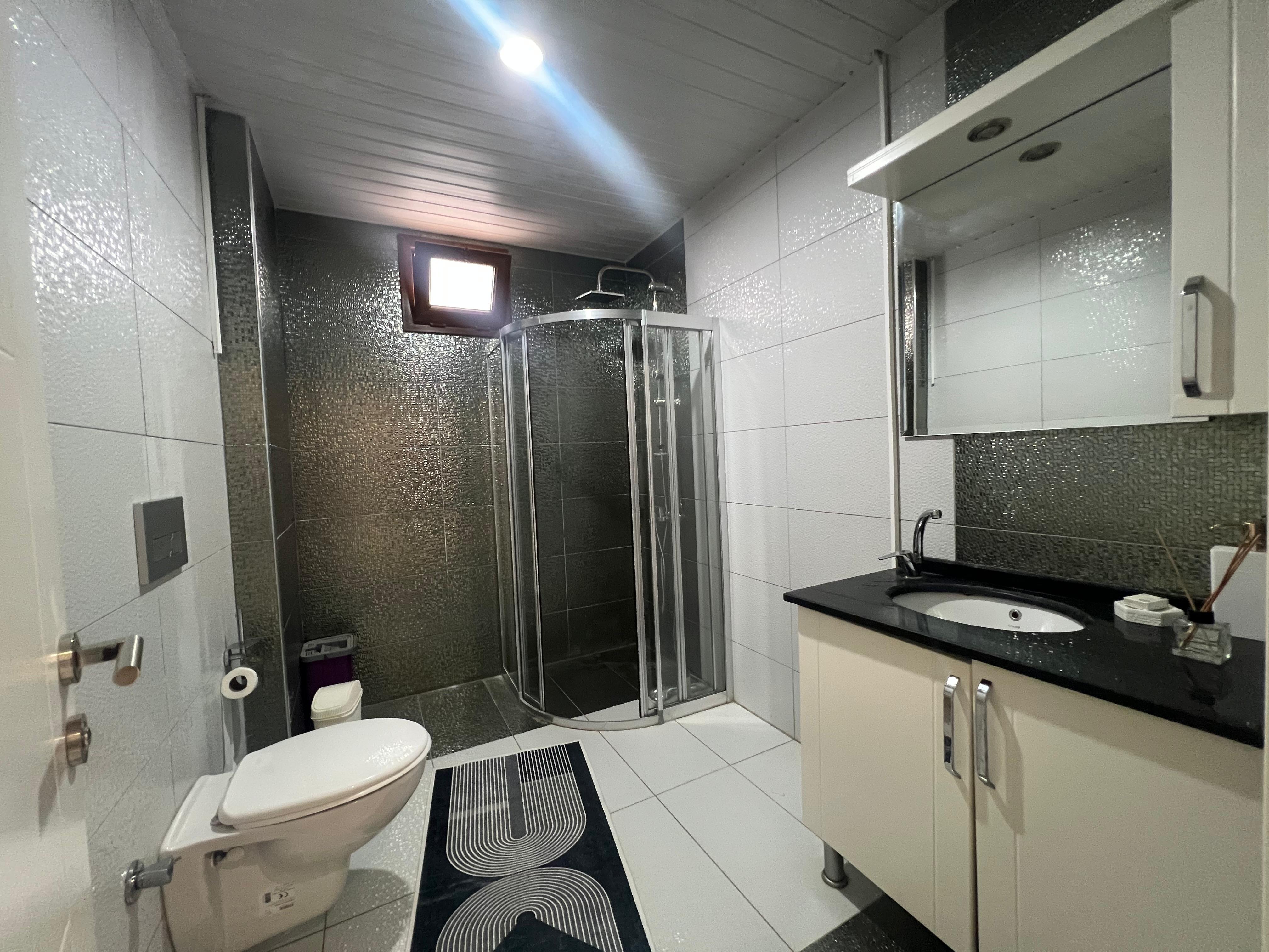 Bathroom with a shower enclosure and dark mosaic tiles in a villa in Kargicak