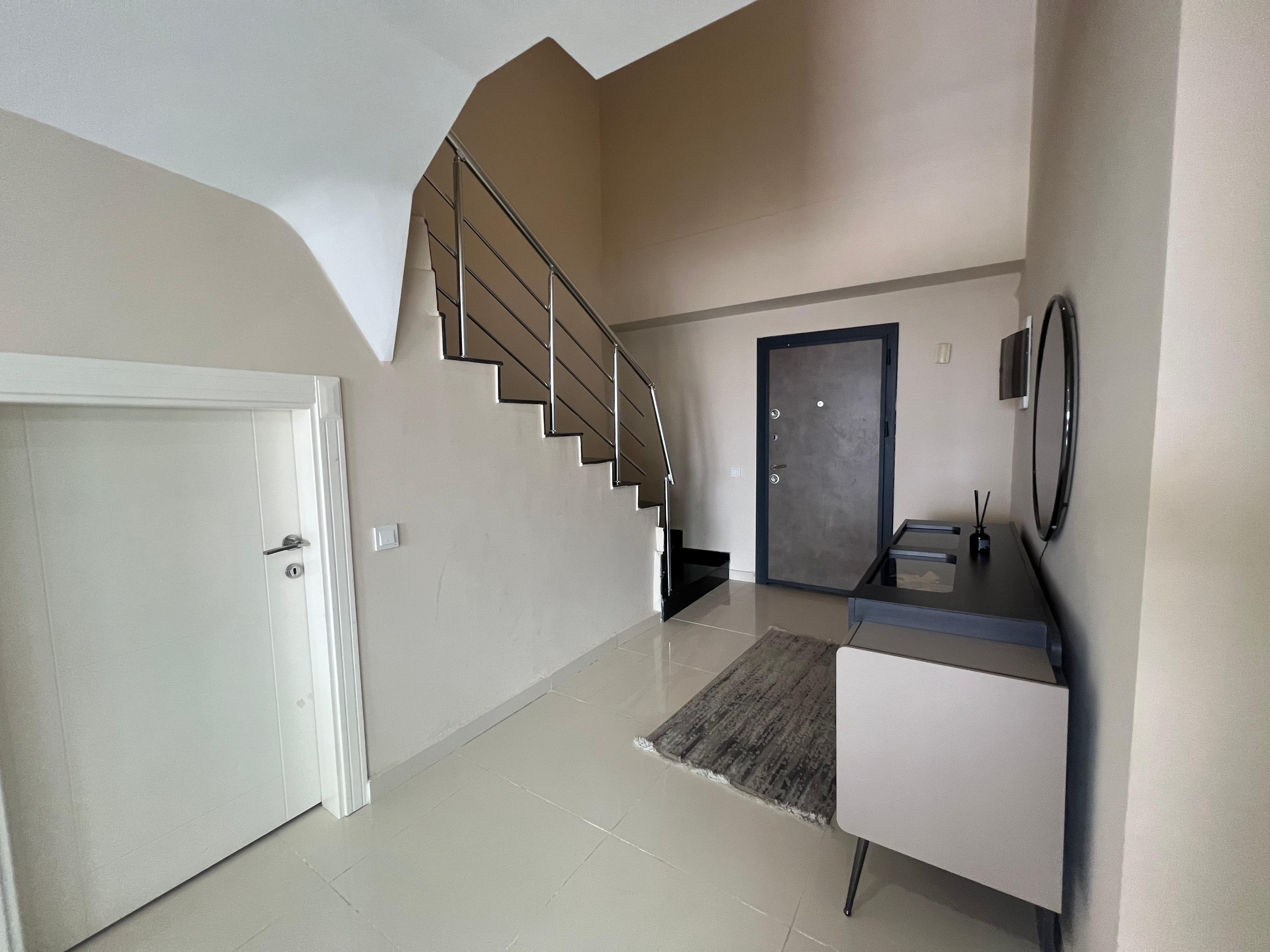 Hall with an internal staircase, console table and round wall mirror