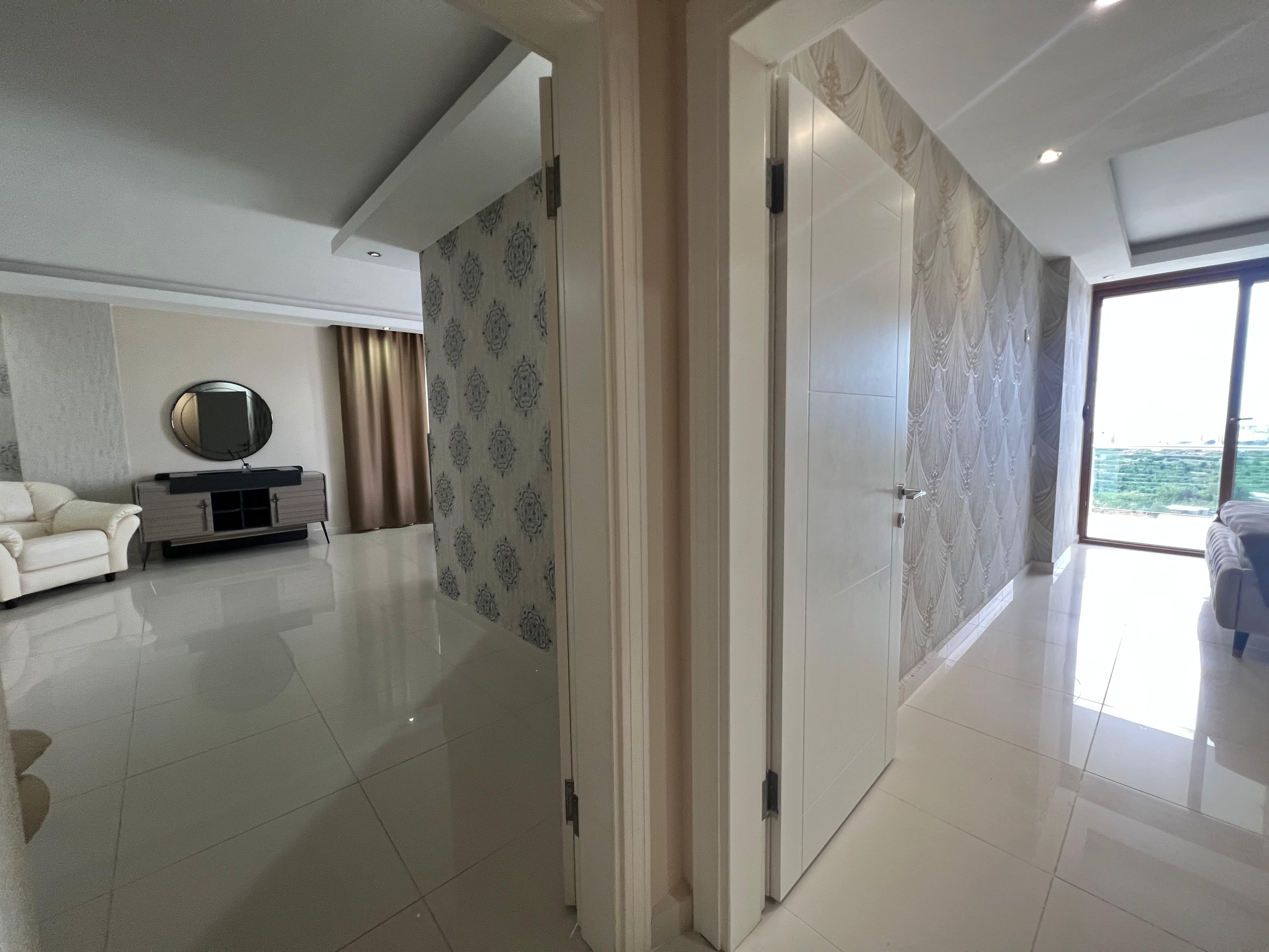 Bright corridor with white doors, patterned wallpaper and glossy tiled flooring in a house in Kargicak