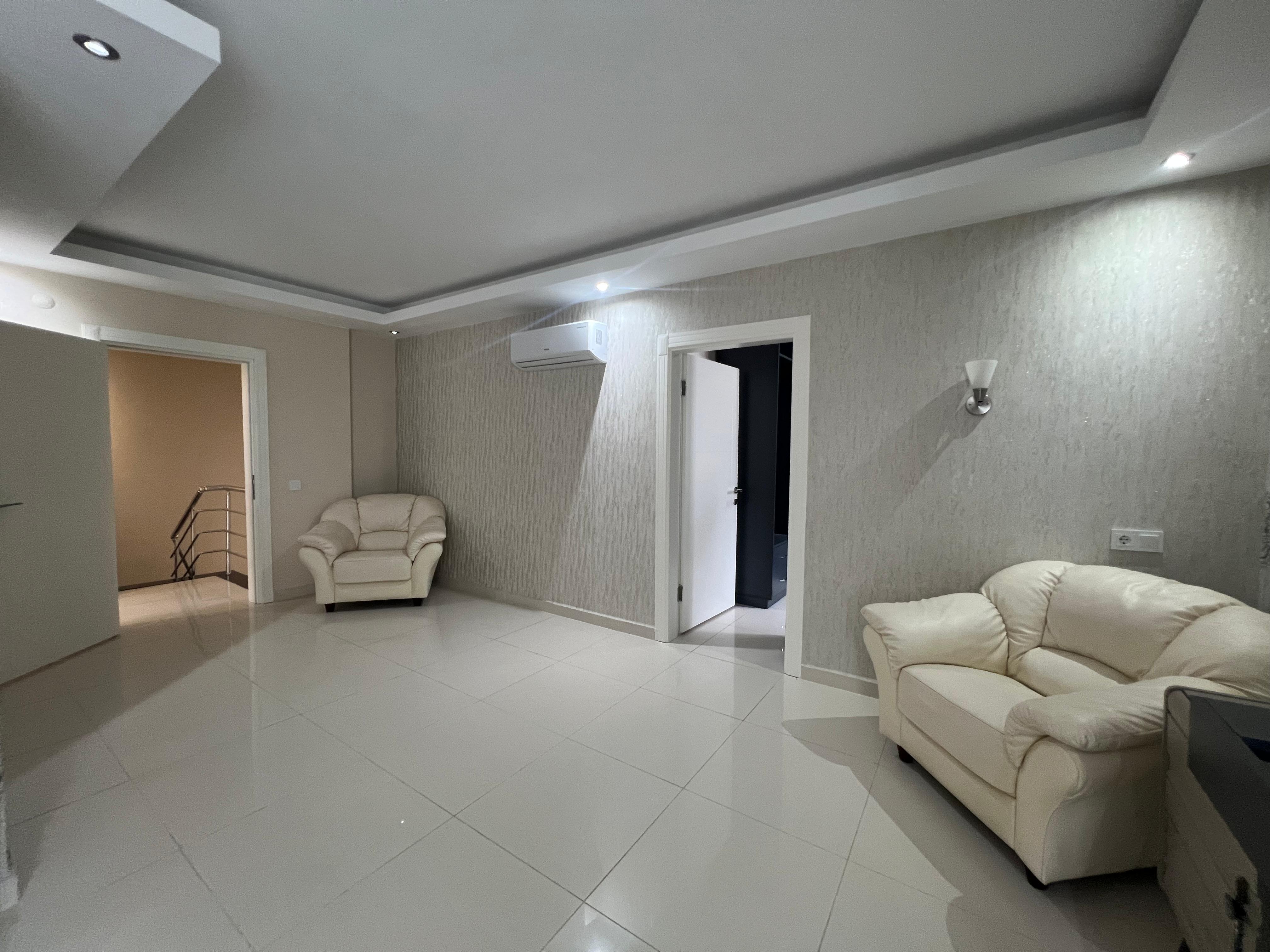 Living room with a white sofa and open hallway door in a villa in Kargicak, Turkey