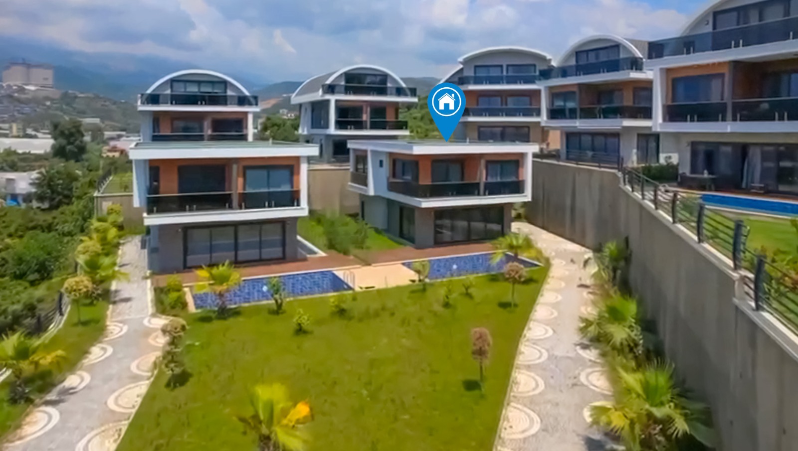 From above, a villa complex with pools and a central green area in Turkey where villas are for sale