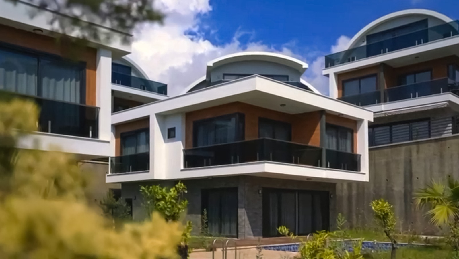 Curved-roof villa facade with panoramic windows and an outdoor pool in Kargicak, Alanya, Turkey