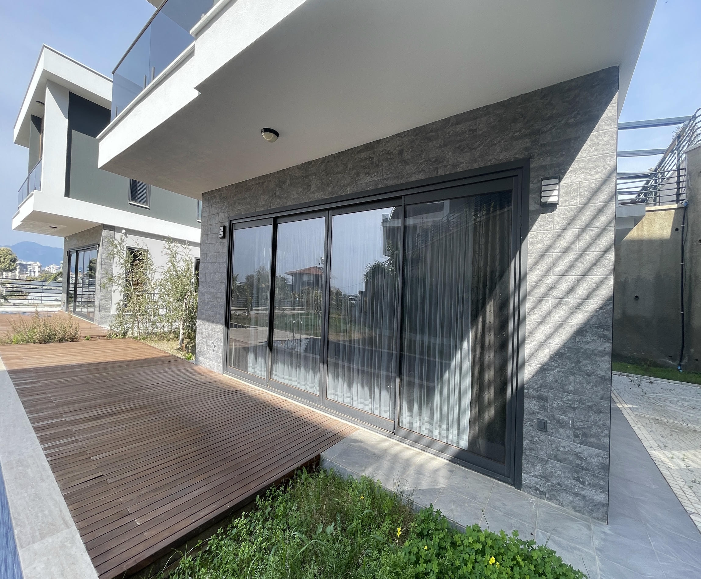 Sliding glass entrance door with dark stone cladding at a villa in Kargicak for sale