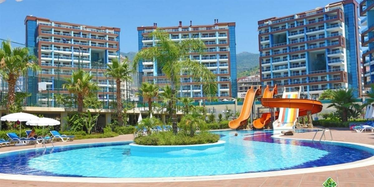 Bitkili yuvarlak adalı kavisli havuz Çikcilli’de kiralama yapılan komplekste dağ yamacına bakıyor