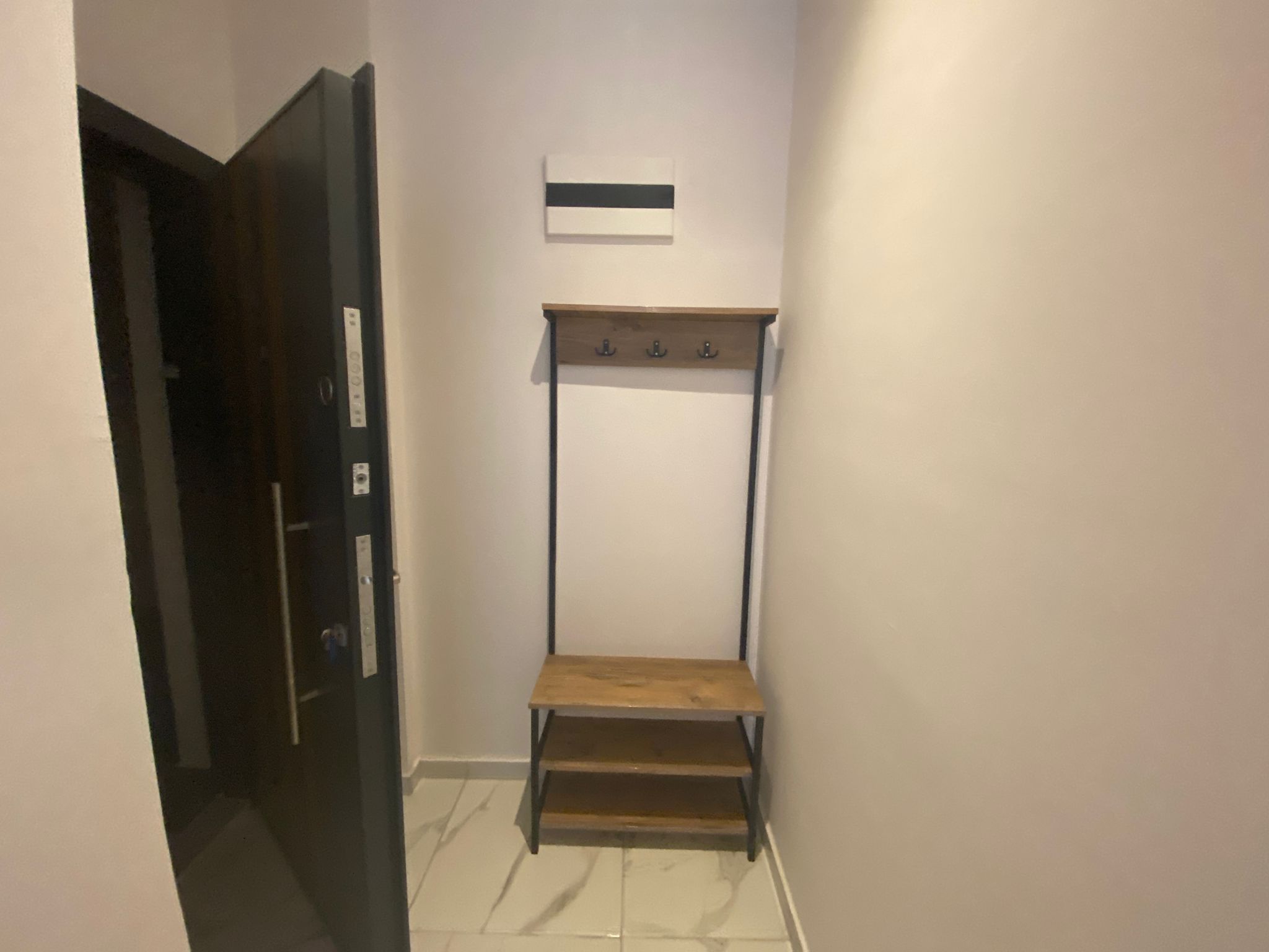 Прихожая с деревянной вешалкой и скамьёй для обуви в квартире 2+1