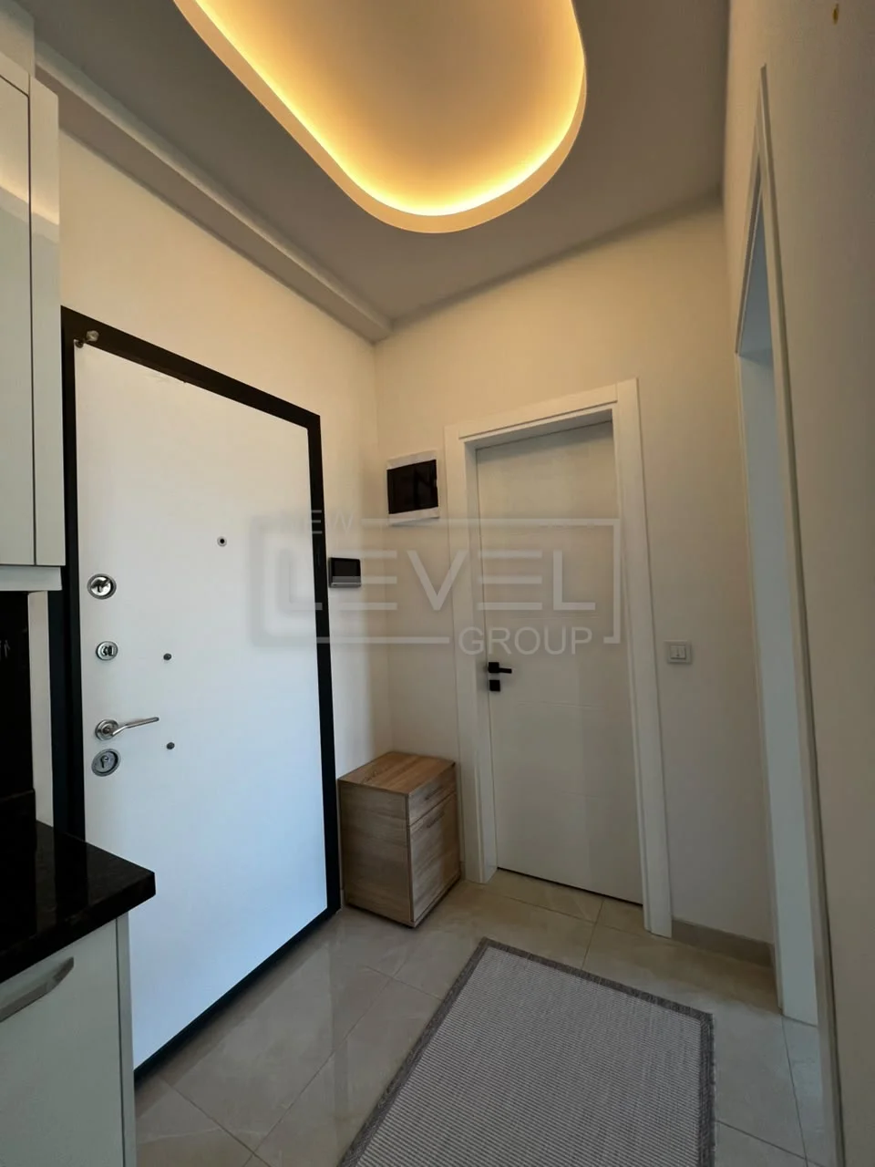 Entrance hall with two white doors a wooden console and a gray floor mat in an apartment