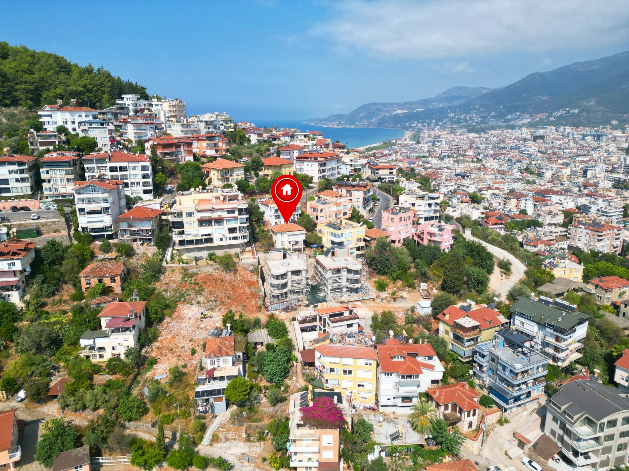Hillside neighborhoods with a bay and mountain ridge show a home for sale