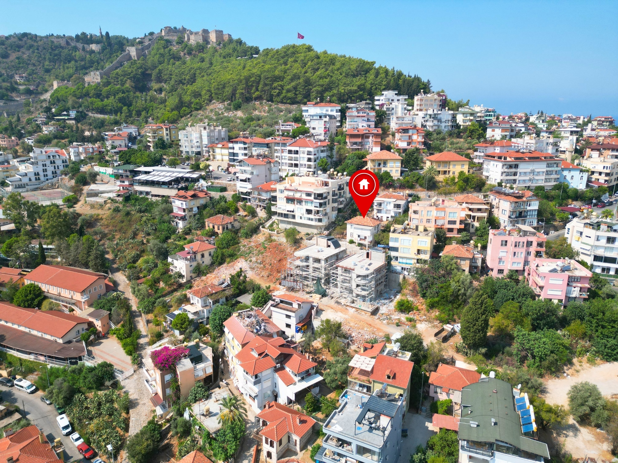 Rolling residential quarters with red roofs and a sea horizon show a villa in Alanya