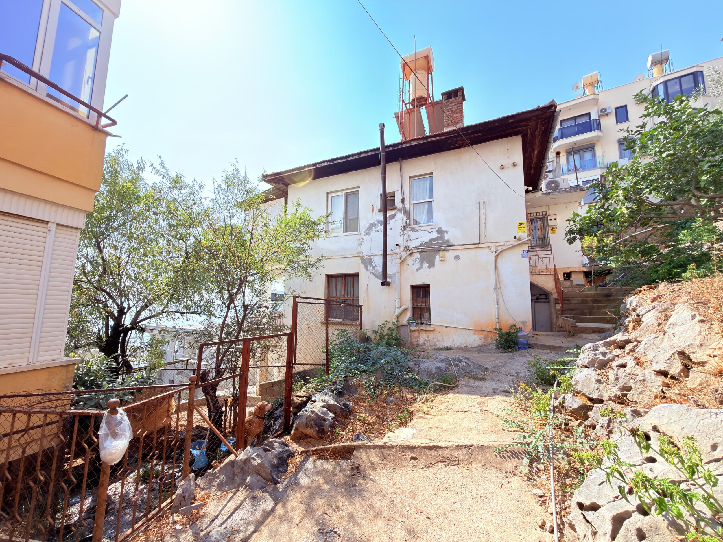 A two-story house with a terracotta roof and metal staircase in Alanya