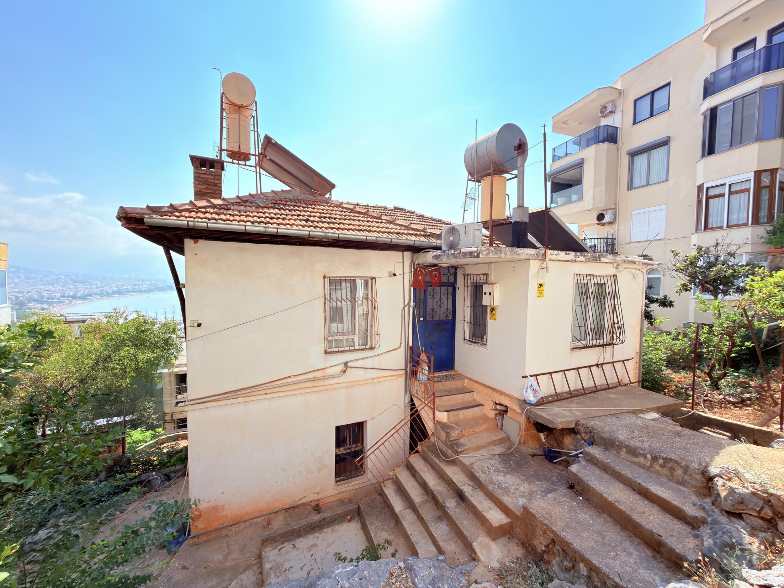 A single-story house with a blue door and partial sea view in Turkey for sale