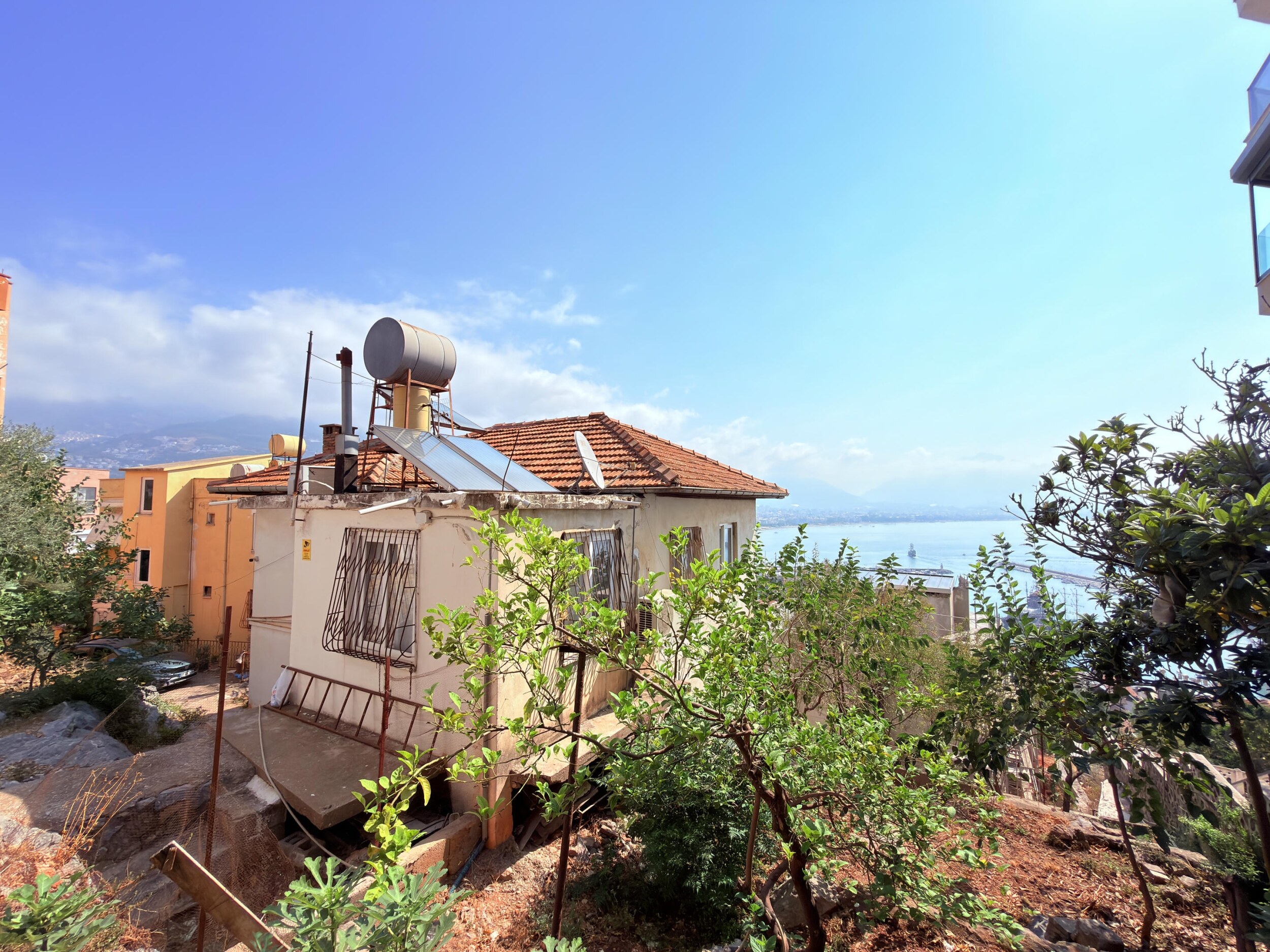 A two-story house with a solar water heater and fruit trees in Turkey