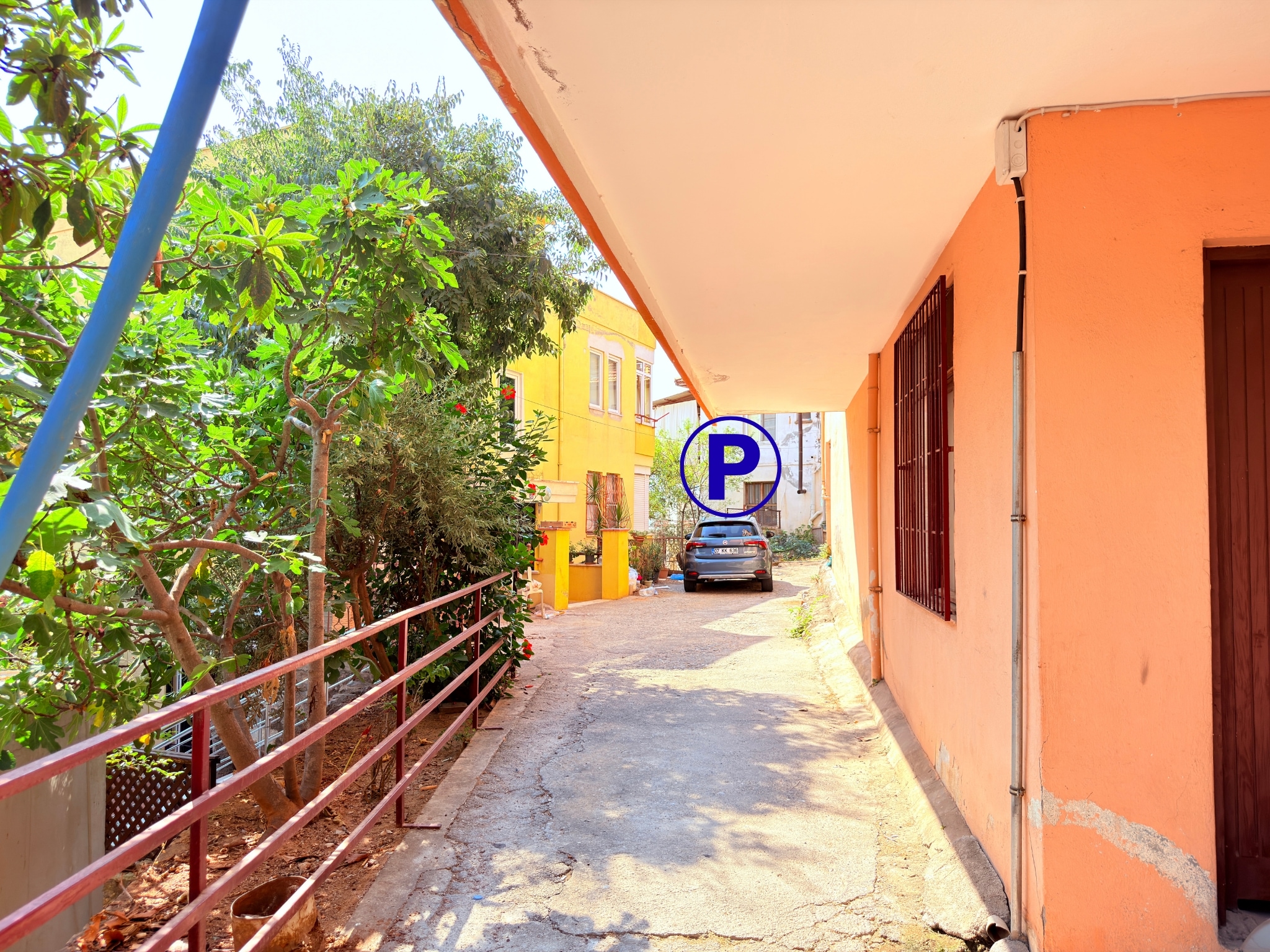 A covered walkway with red railings and green shrubs in Alanya where homes are for sale