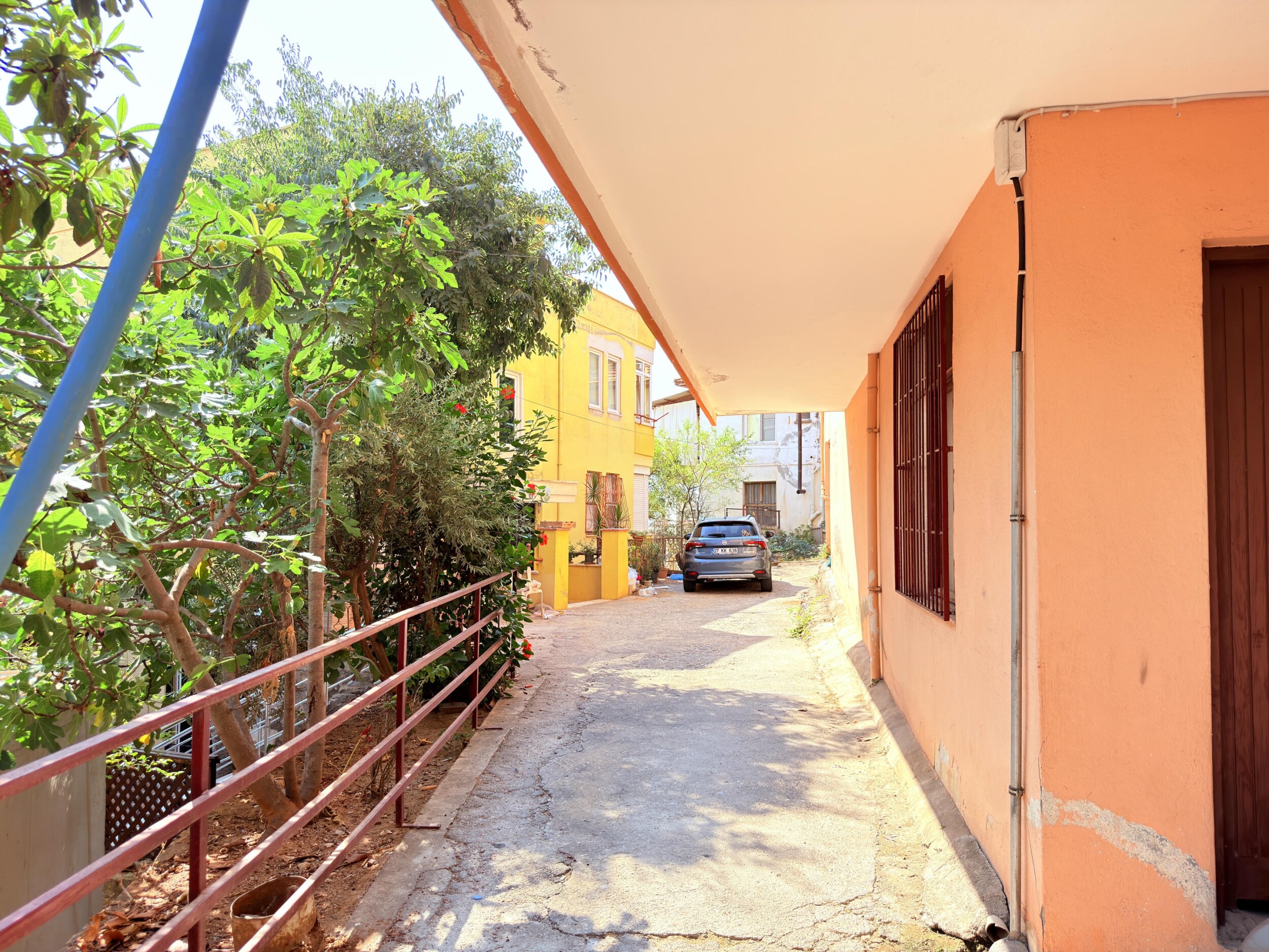 A covered walkway with red railings and green trees in Alanya, Turkey