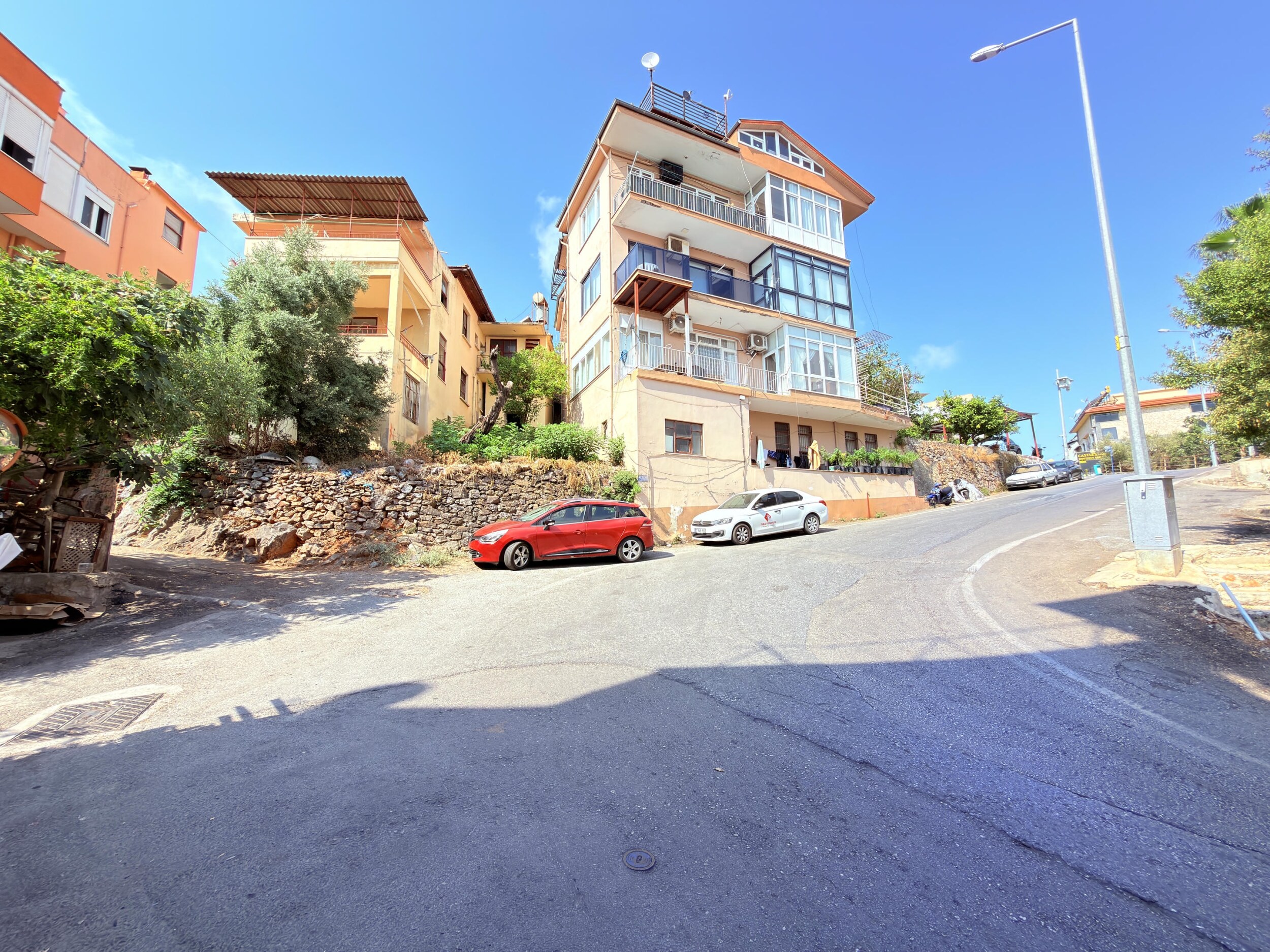 A broad road intersection with hillside homes and stone terrain in Alanya
