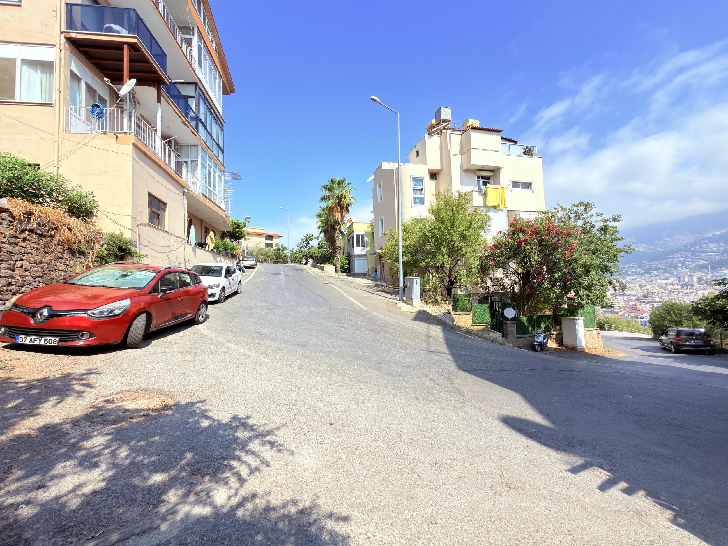 A sloping street with balconies and a palm tree beside a villa in Alanya, Turkey