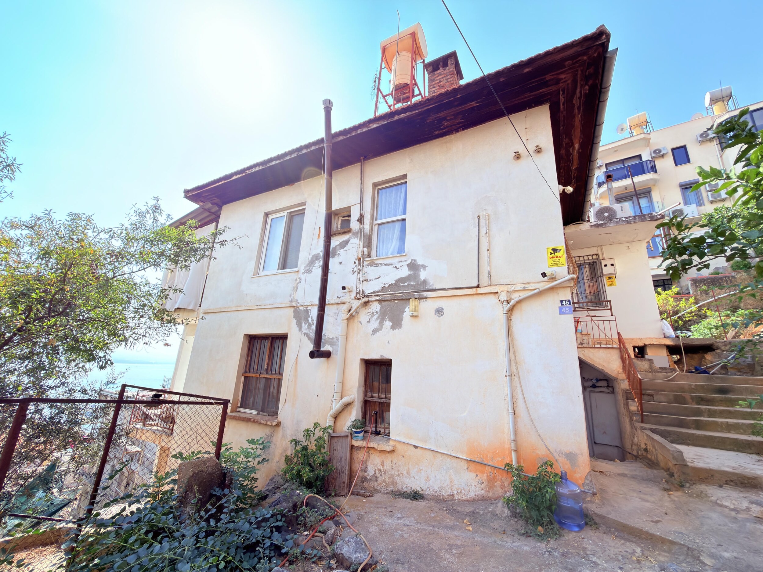 A two-story house with a dark tiled roof and concrete staircase in Turkey for sale