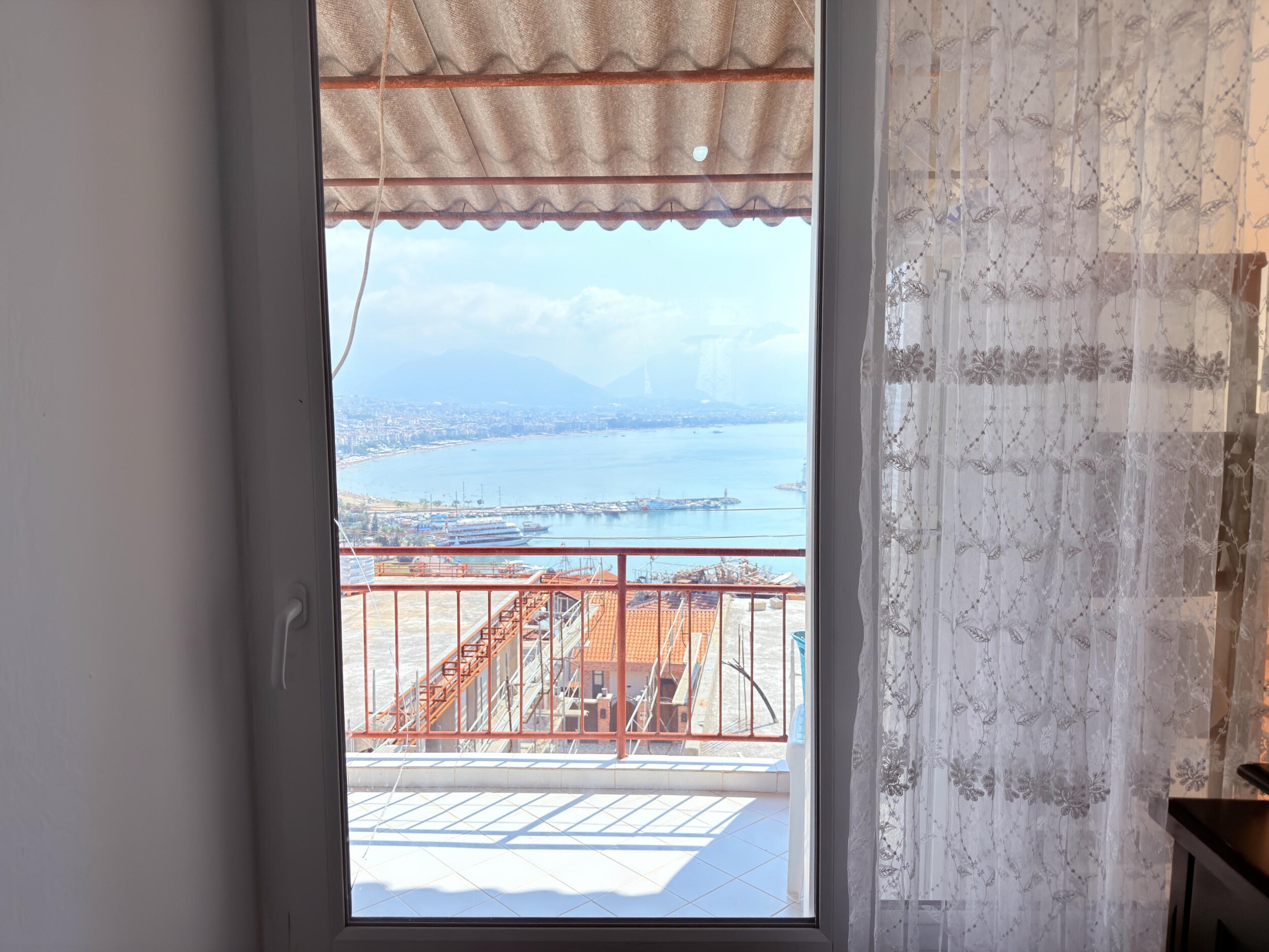 A balcony with red railings and a panoramic harbor view in Alanya