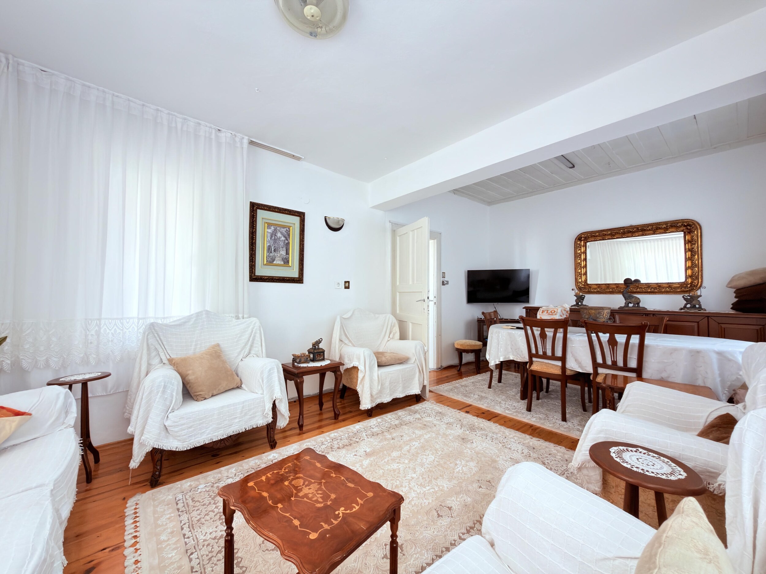 A living room with covered sofas, carved table and dining area is offered for sale
