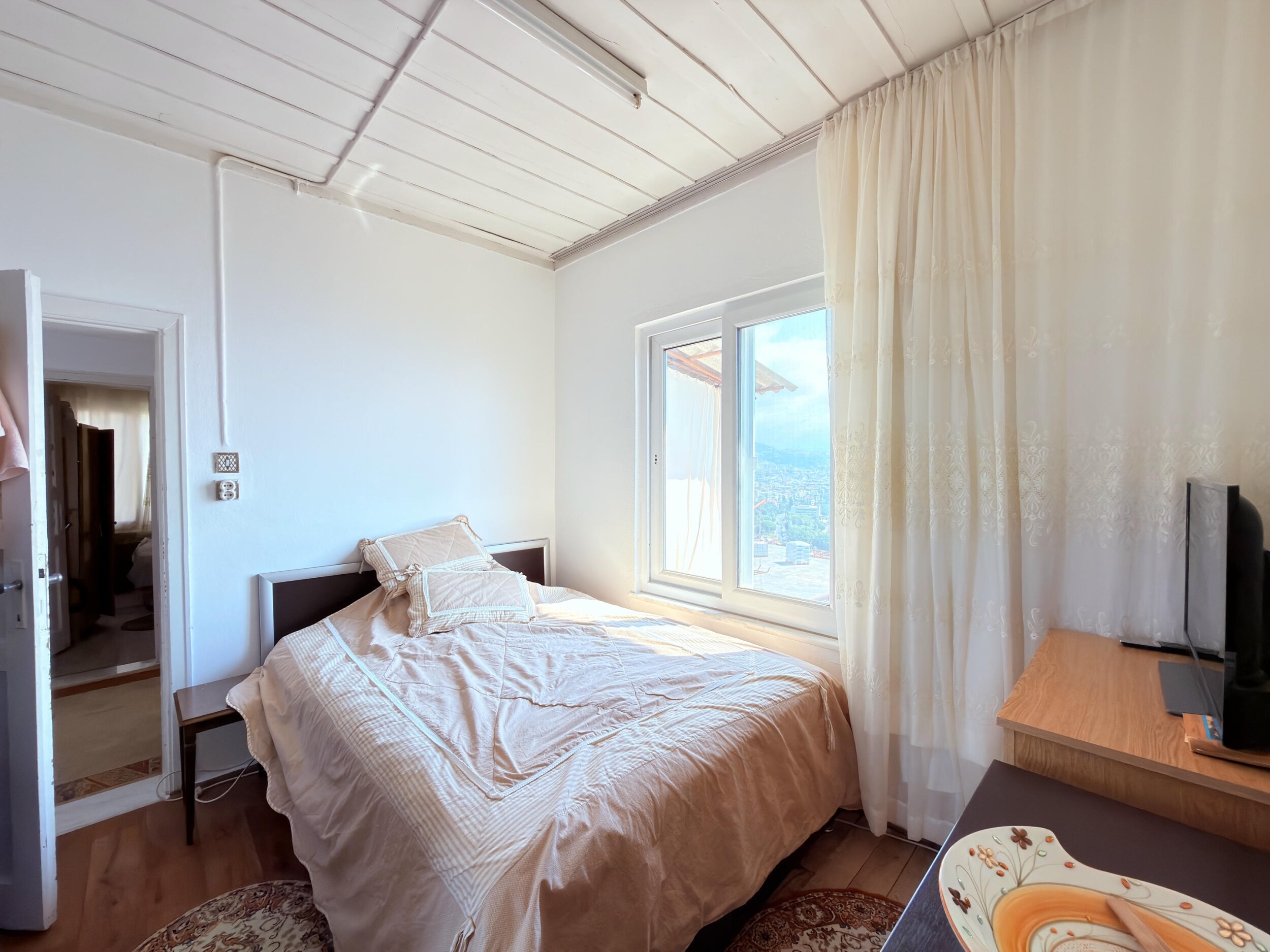 A bedroom with a double bed, light walls and television in a villa in Alanya
