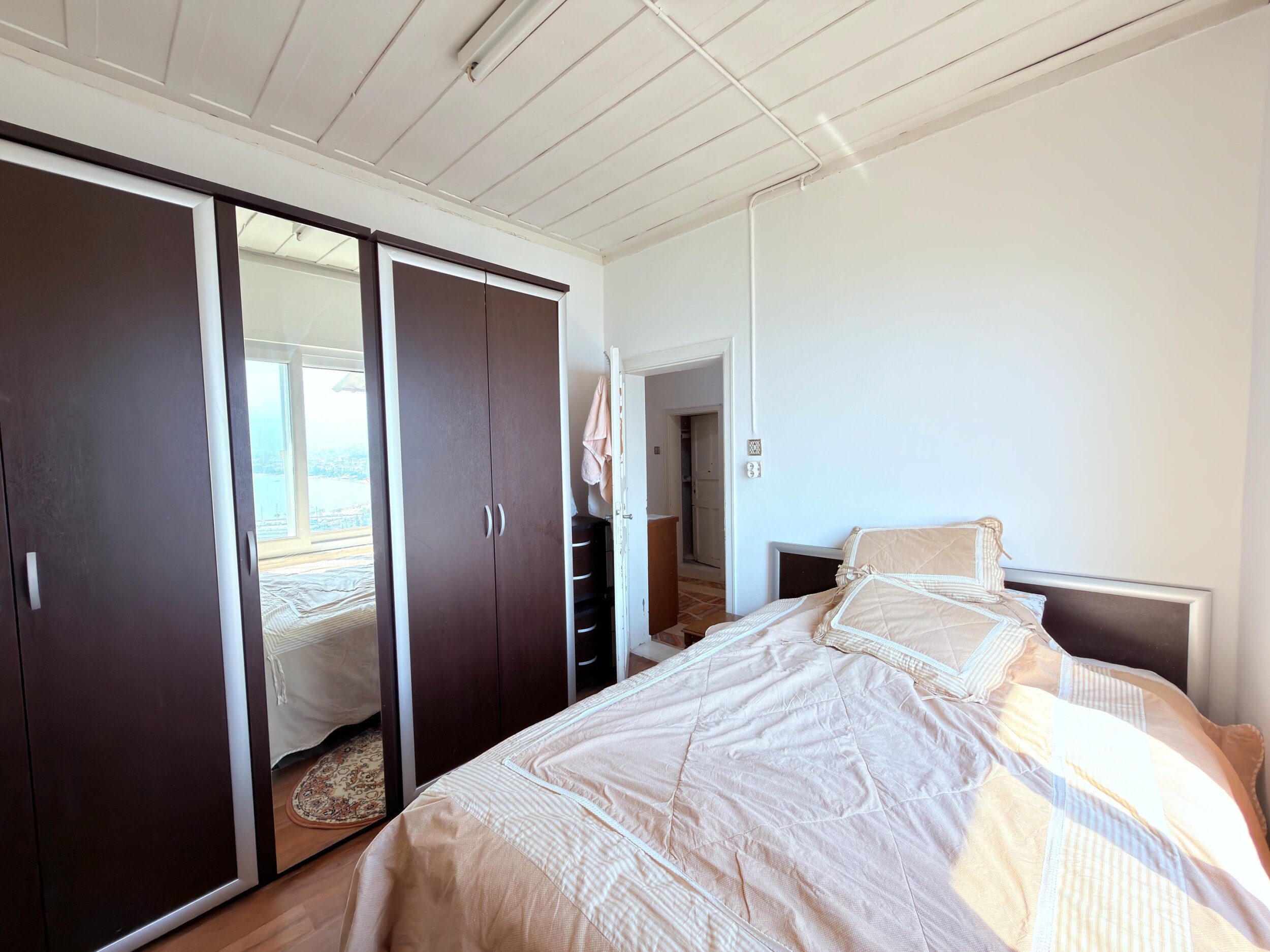 A villa bedroom with a double bed, mirrored wardrobe and wooden floor