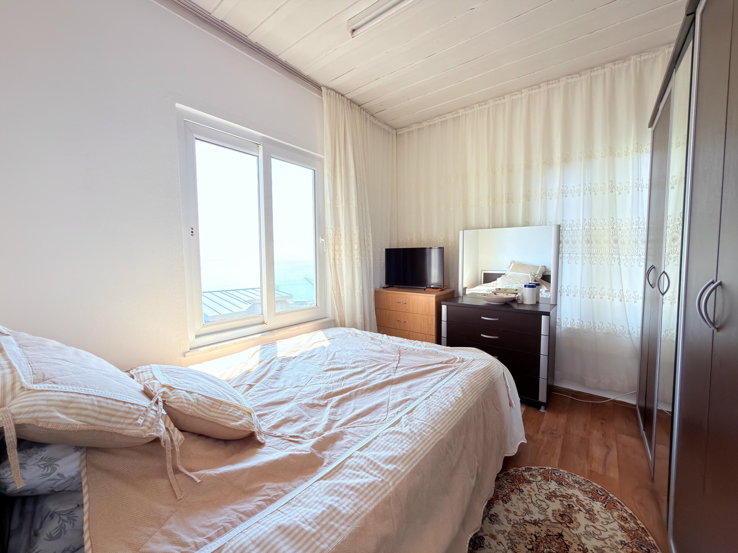 A bedroom with a mirrored wardrobe, dresser and television in Alanya