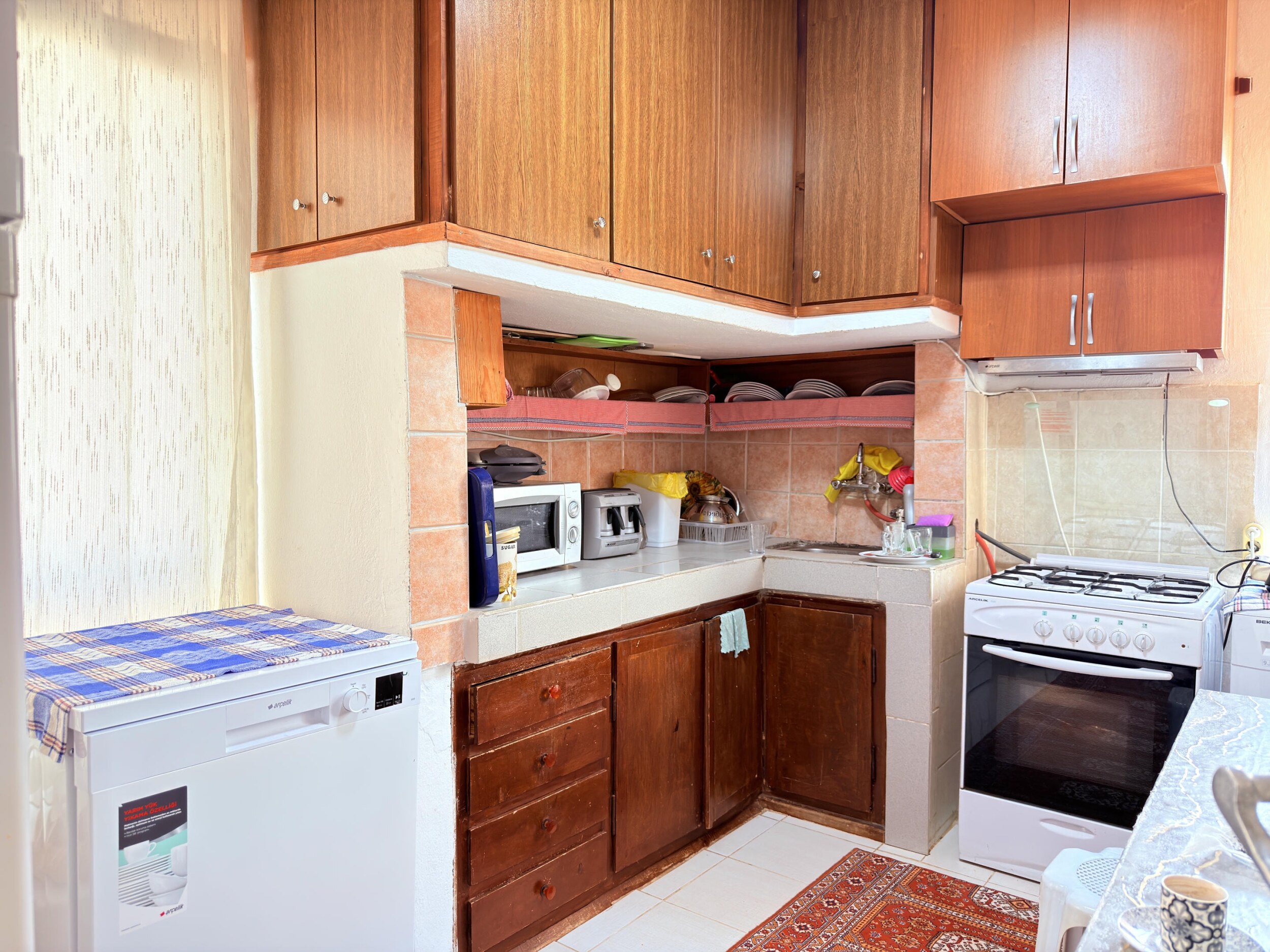 A kitchen with dark wood cabinets, gas stove and dishwasher in a villa in Alanya
