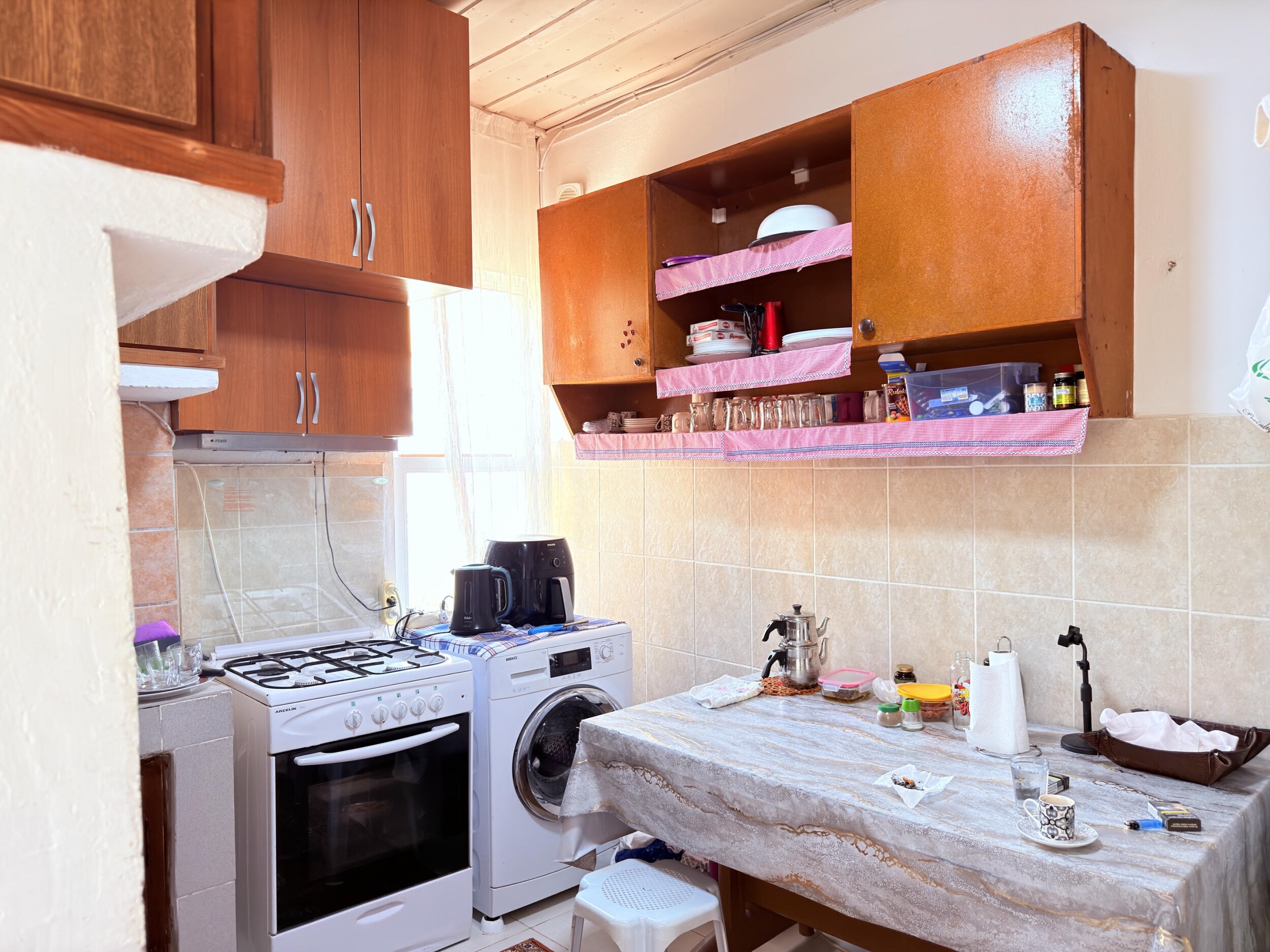A wooden kitchen with gas stove, washing machine and dining table in a villa